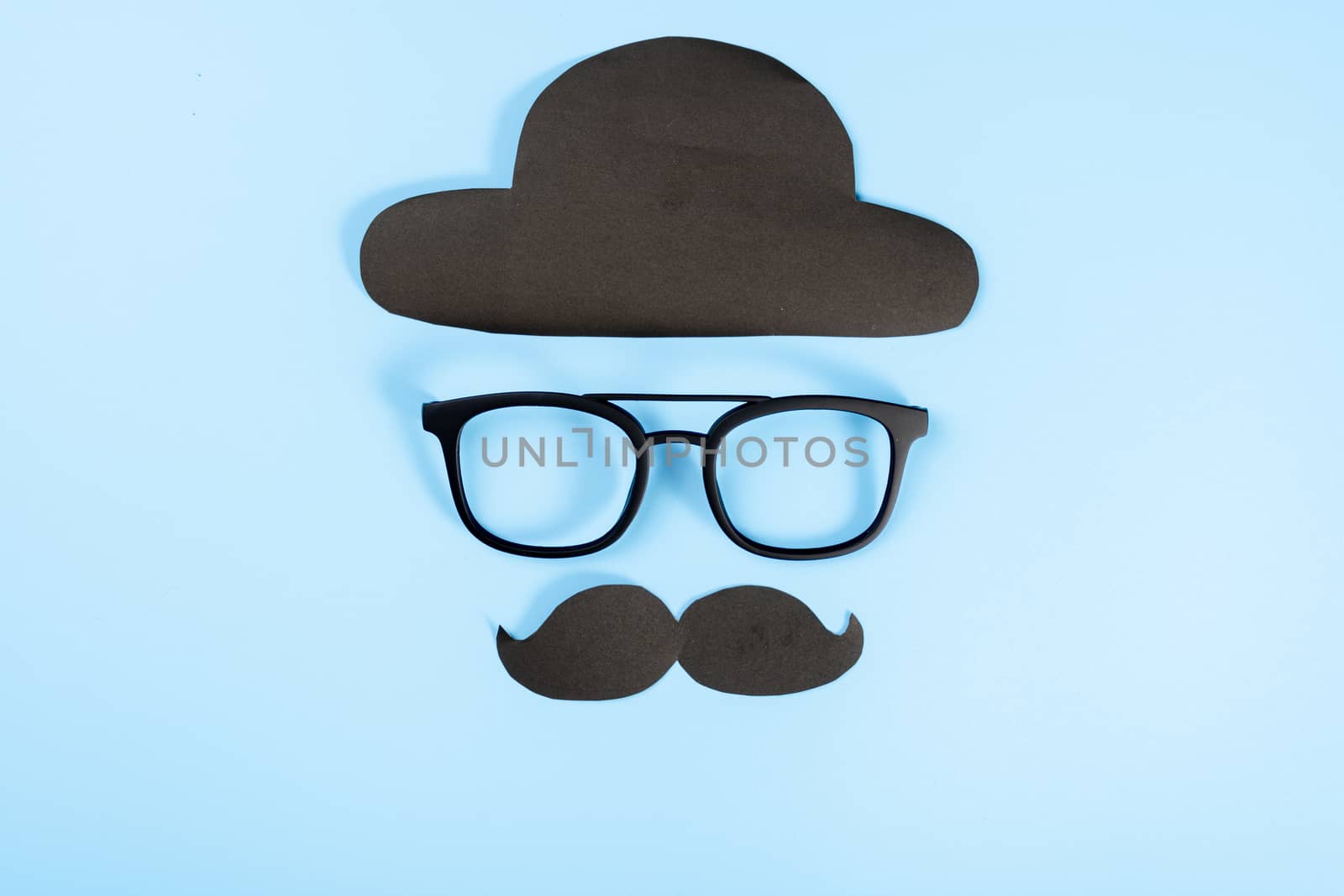 Happy Father Day background concept with glasses, black hat and black mustache on blue background with copy space for text.