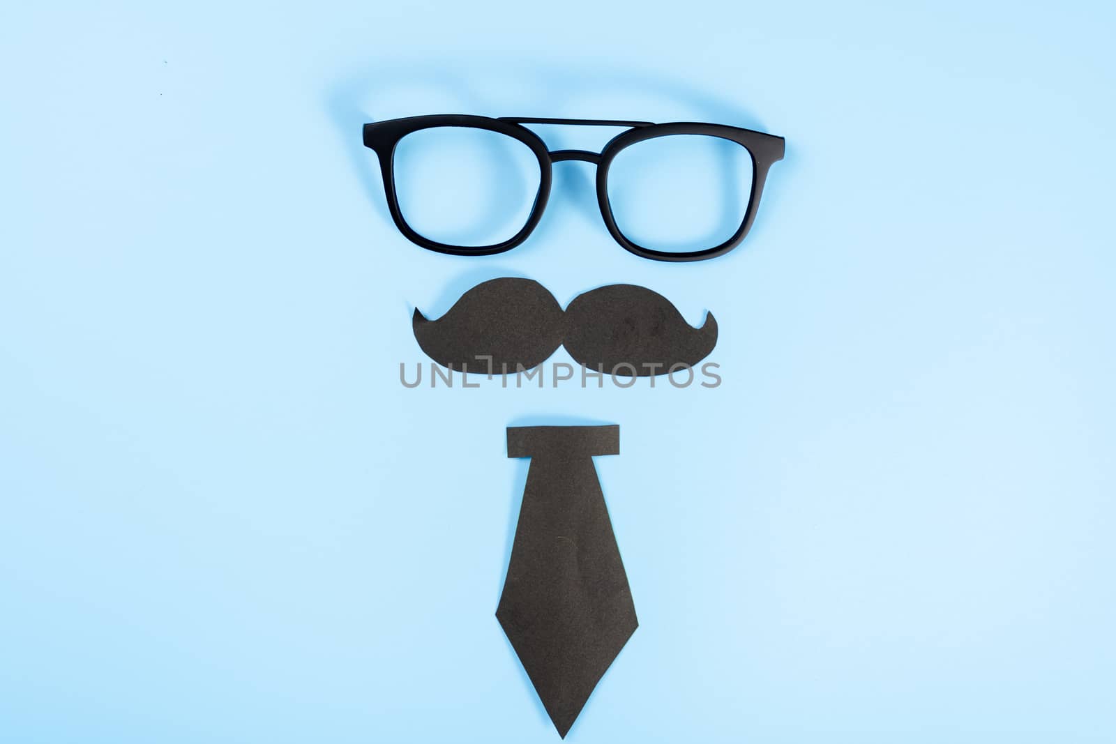 Happy Father Day background concept with glasses, black tie and black mustache on blue background with copy space for text.