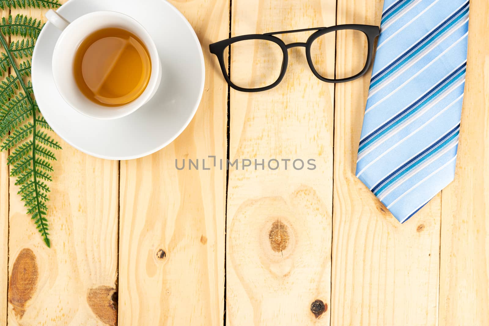 Happy Father Day background concept with blue necktie, glasses and cup of tea on wooden background with copy space for text.