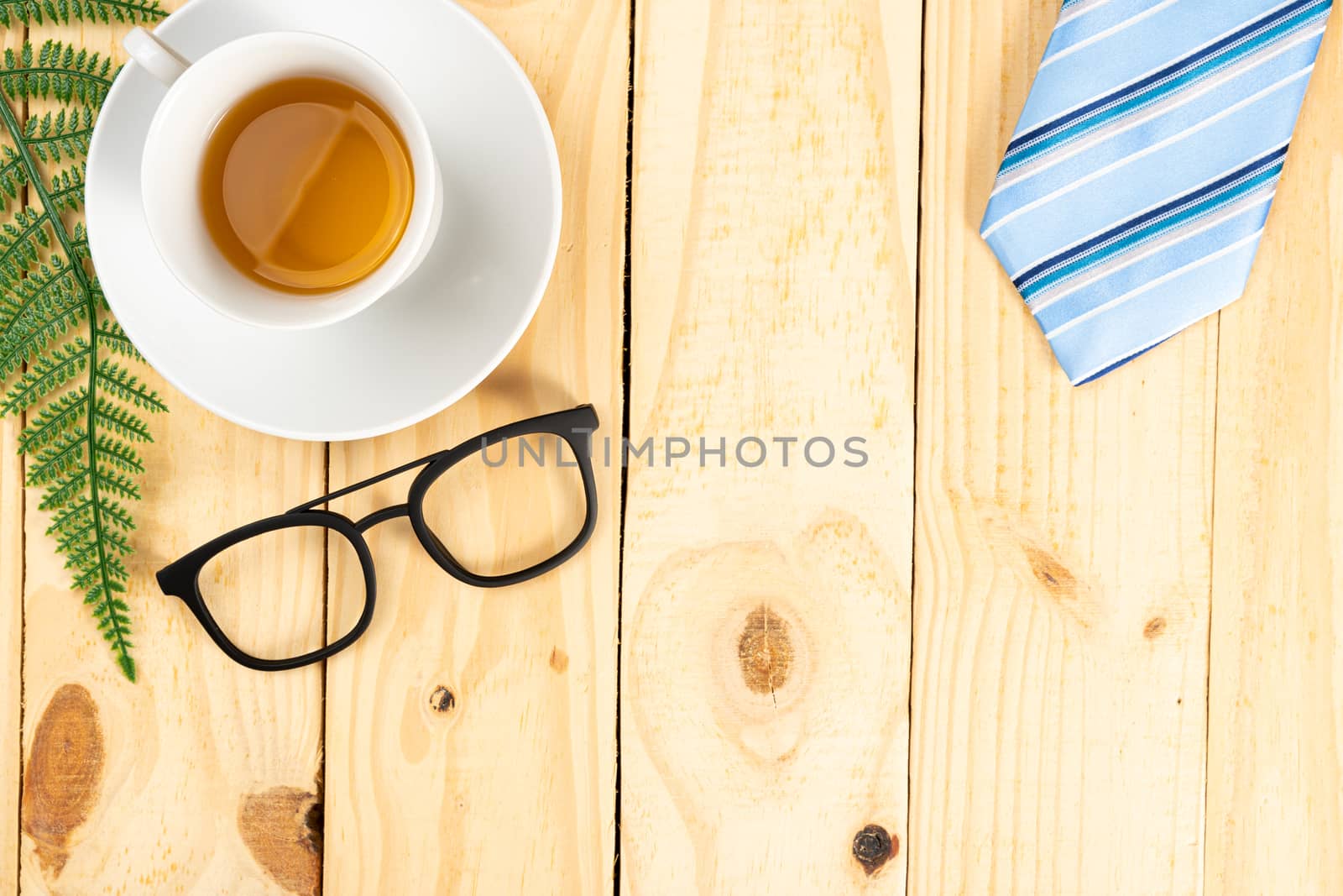 Happy Father Day background concept with blue necktie, glasses and cup of tea on wooden background with copy space for text.