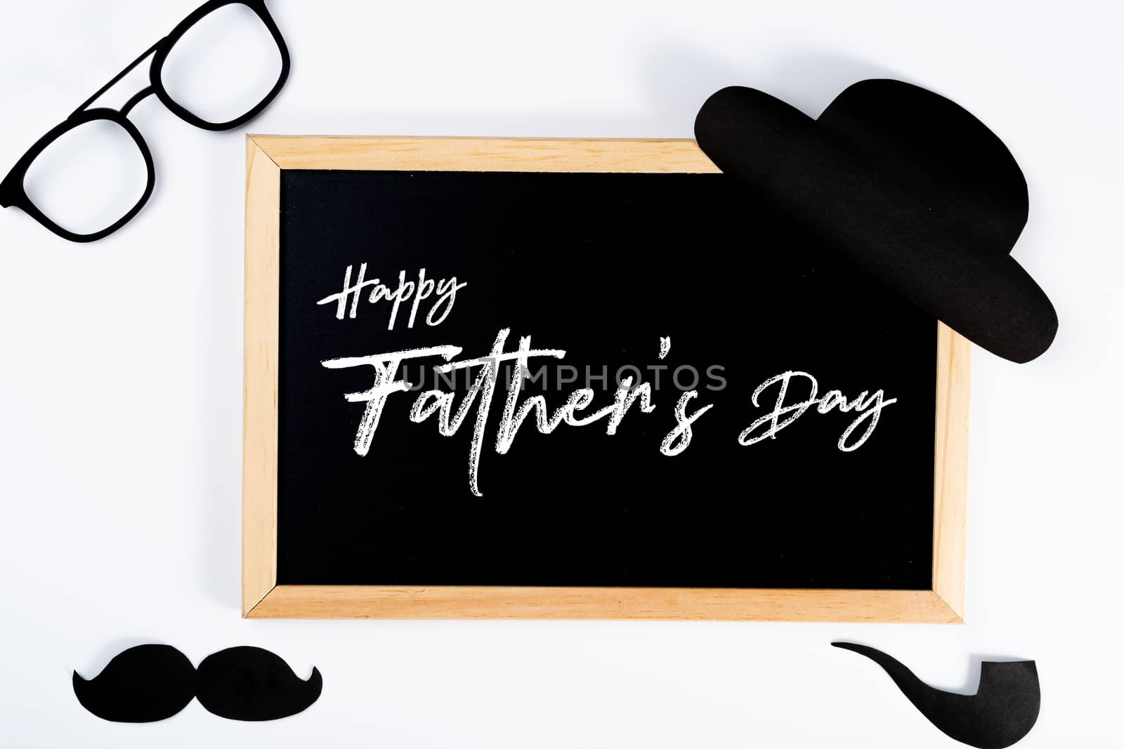 Happy Father Day background concept with blackboard and paper cut of hat, glasses, black mustache and smoking pipe on white background with copy space for text.