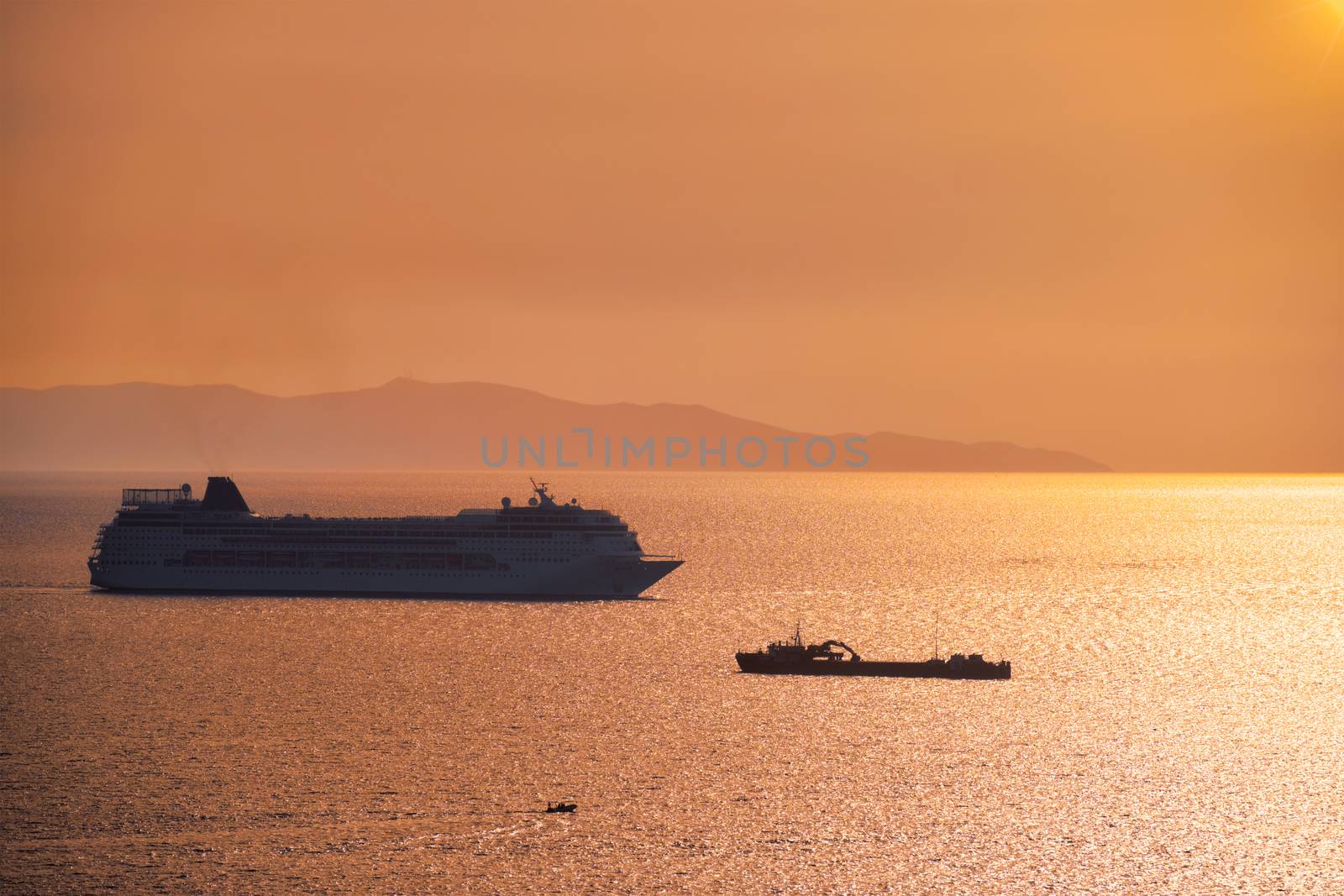 Cruise ship silhouette in Aegean sea on sunset. Mykonos island, Greece