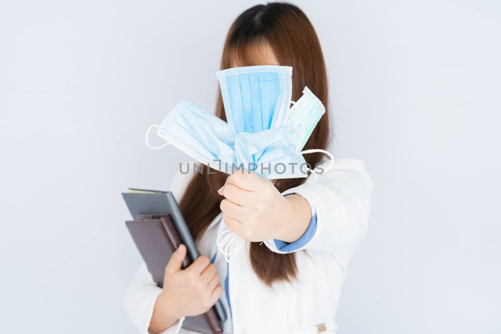 Business woman shows hand grasping mask over grey background. Back to the normal concept.