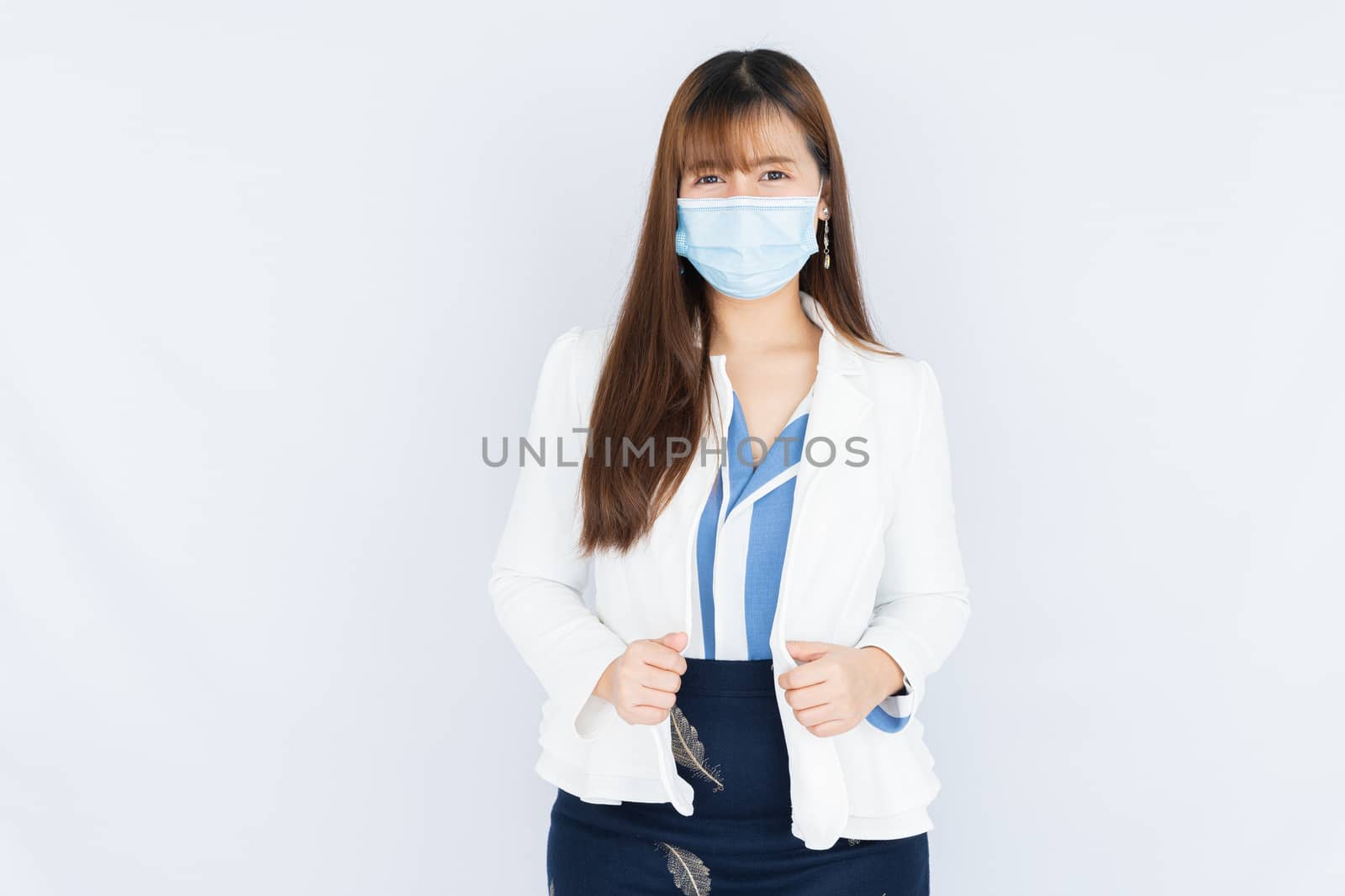Smiling Asian business woman wearing a medical face mask and looking at the camera the over grey background. Back to the normal concept.