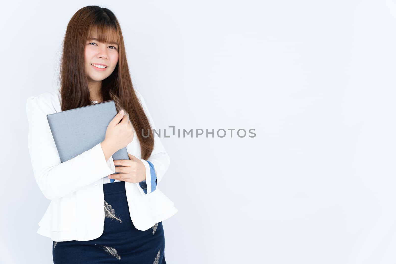 Smiling Asian business woman holding the notebook and looking at the camera over grey background. Back to the normal concept.