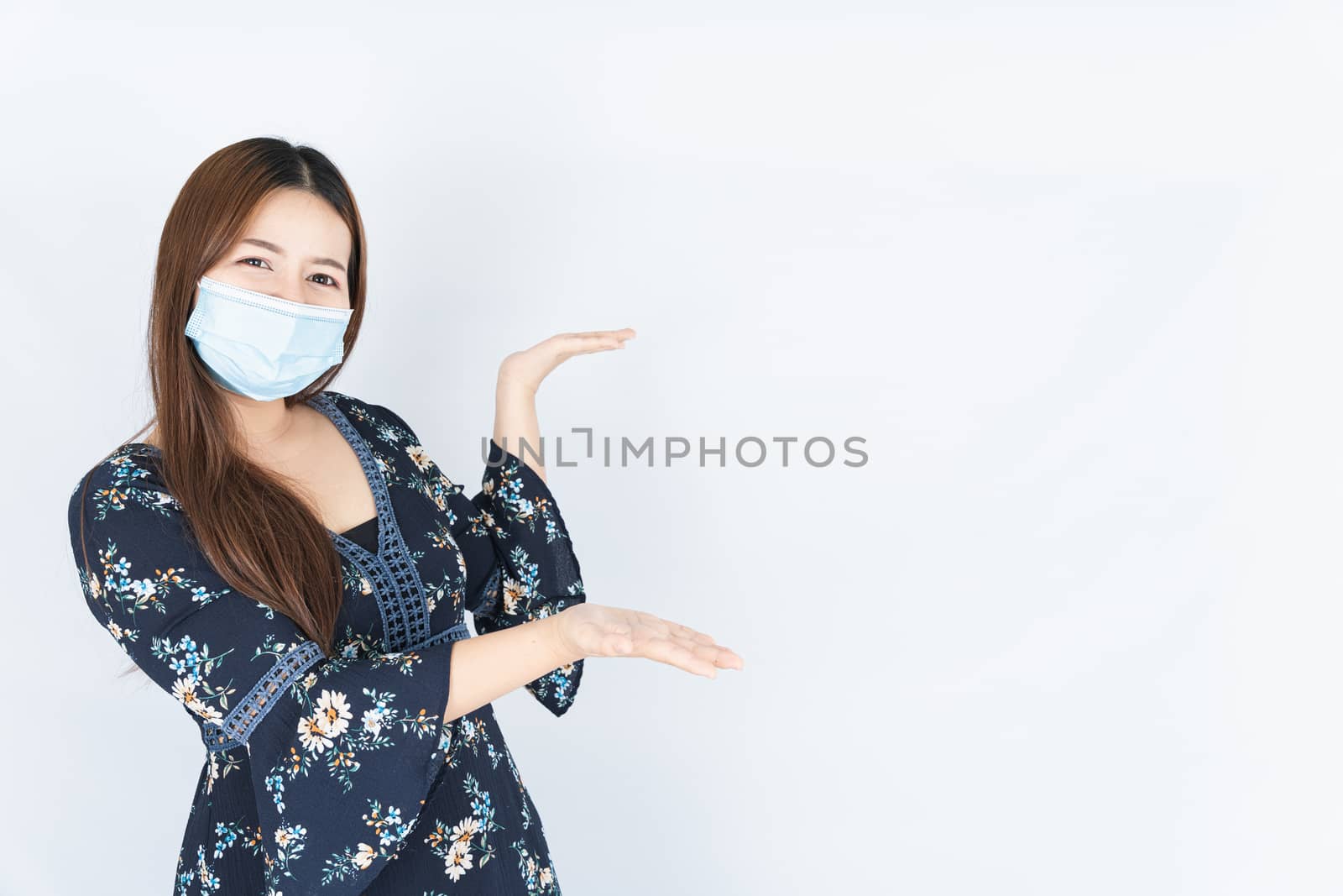 Asian beautiful happy hipster woman wearing a medical protection face mask for protect the coronavirus, filter dust PM 2.5 and cold and her finger pointing outside on the white background