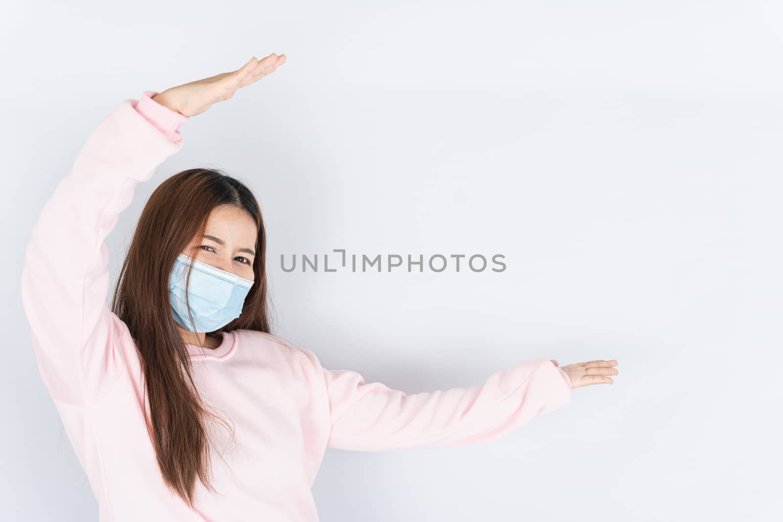 Asian beautiful happy hipster woman wearing a medical protection face mask for protect the coronavirus, filter dust PM 2.5 and cold and her finger pointing outside on the white background