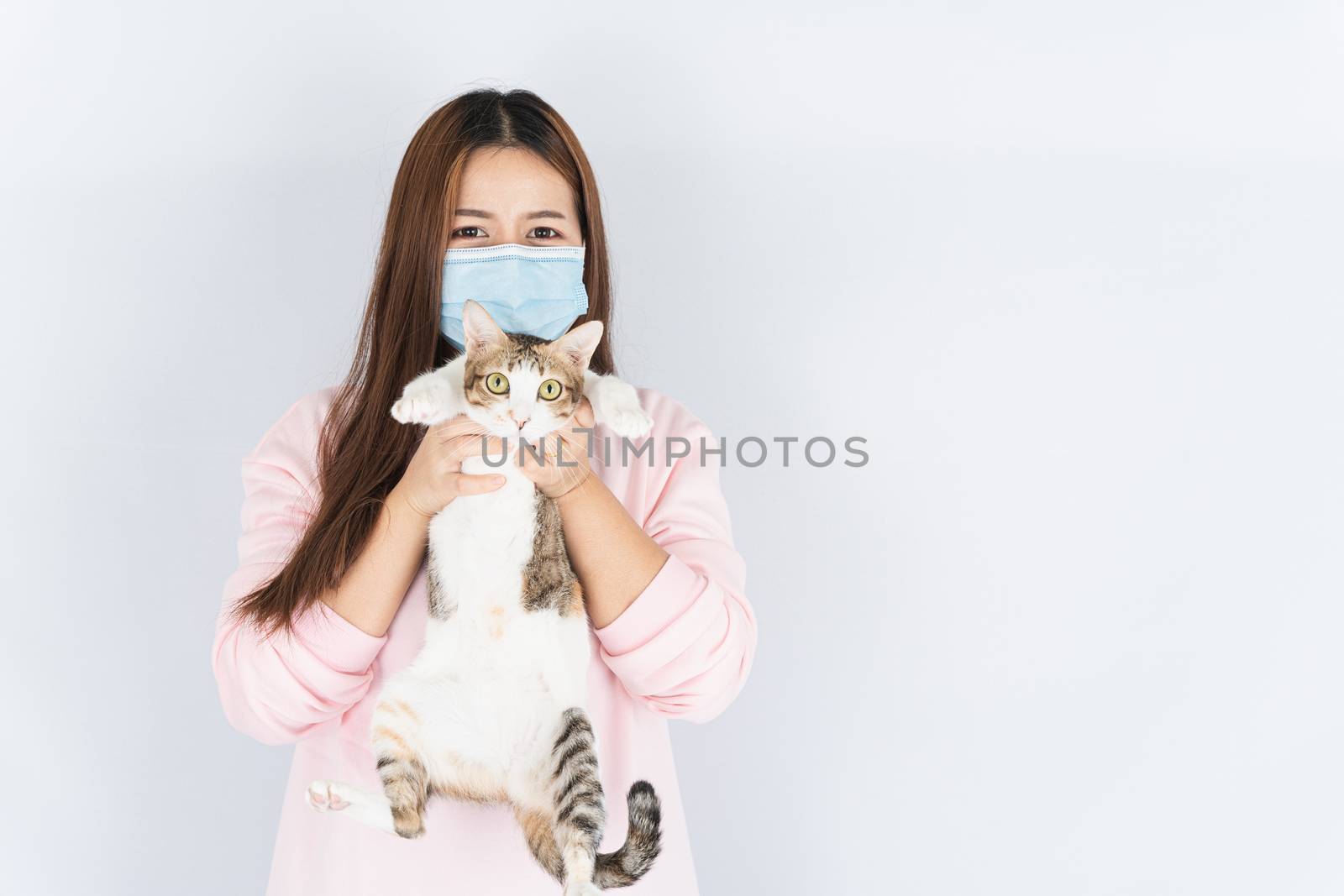 Asian beautiful happy woman wearing a medical protection face mask for protect the coronavirus, filter dust PM 2.5, cold and allergic to cat fur and she carry a cat on the white background