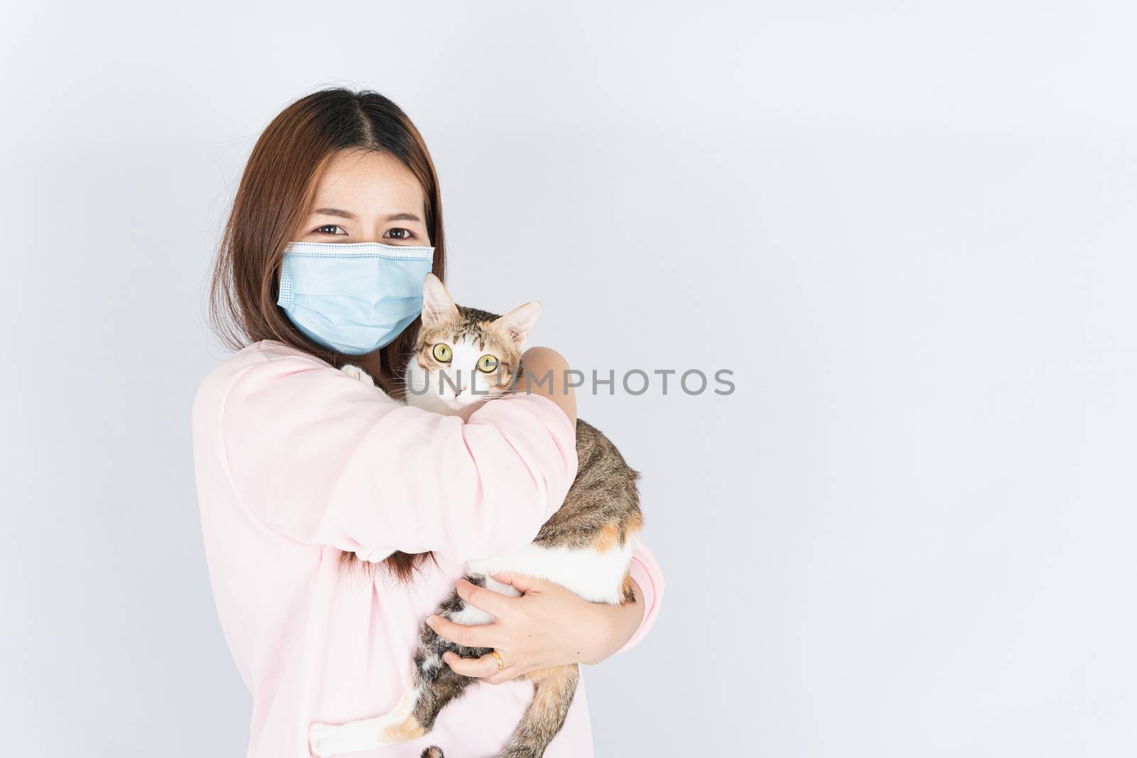 Asian beautiful happy woman wearing a medical protection face mask for protect the coronavirus, filter dust PM 2.5, cold and allergic to cat fur and she carry a cat on the white background