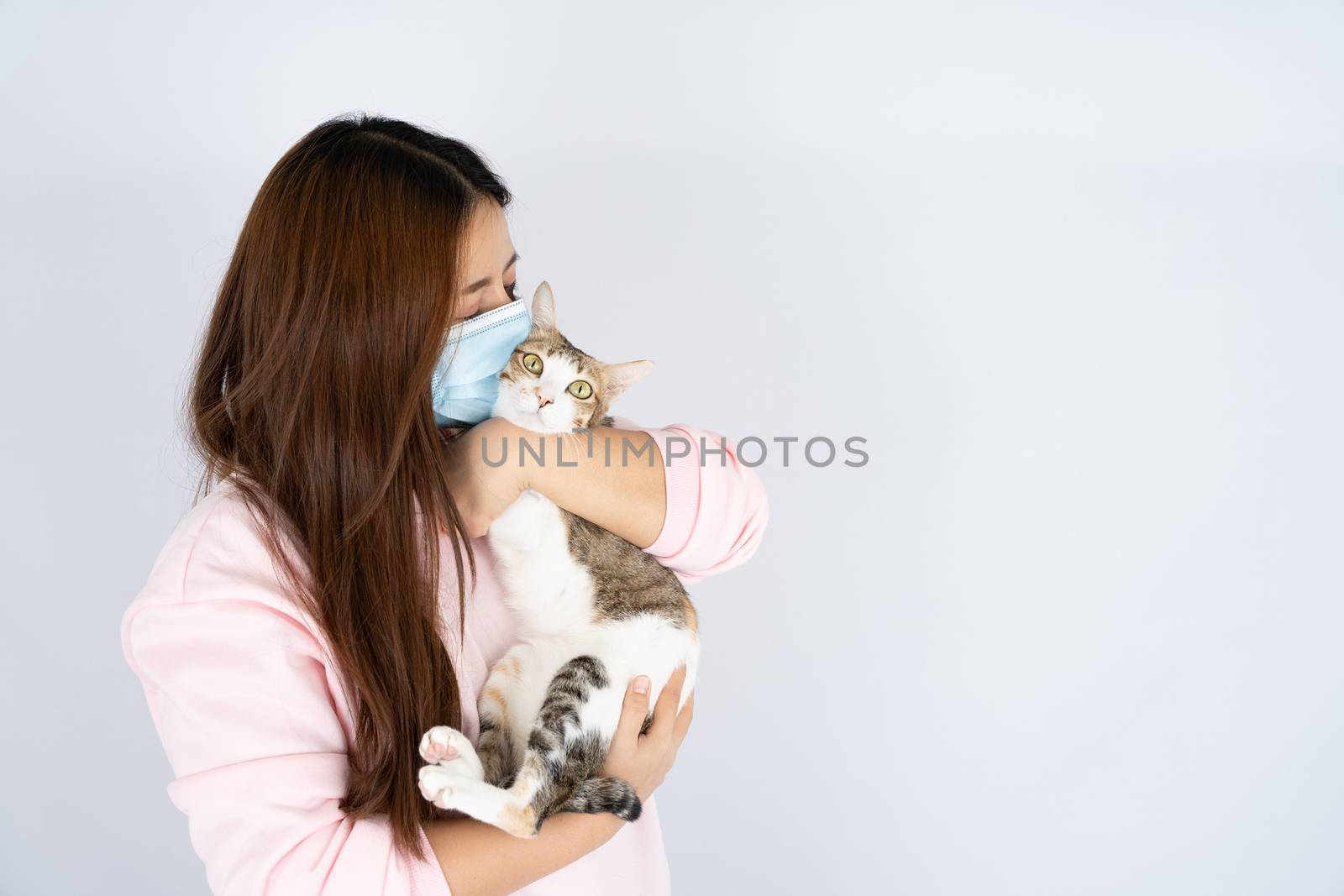 Asian beautiful happy woman wearing a medical protection face mask for protect the coronavirus, filter dust PM 2.5, cold and allergic to cat fur and she carry a cat on the white background