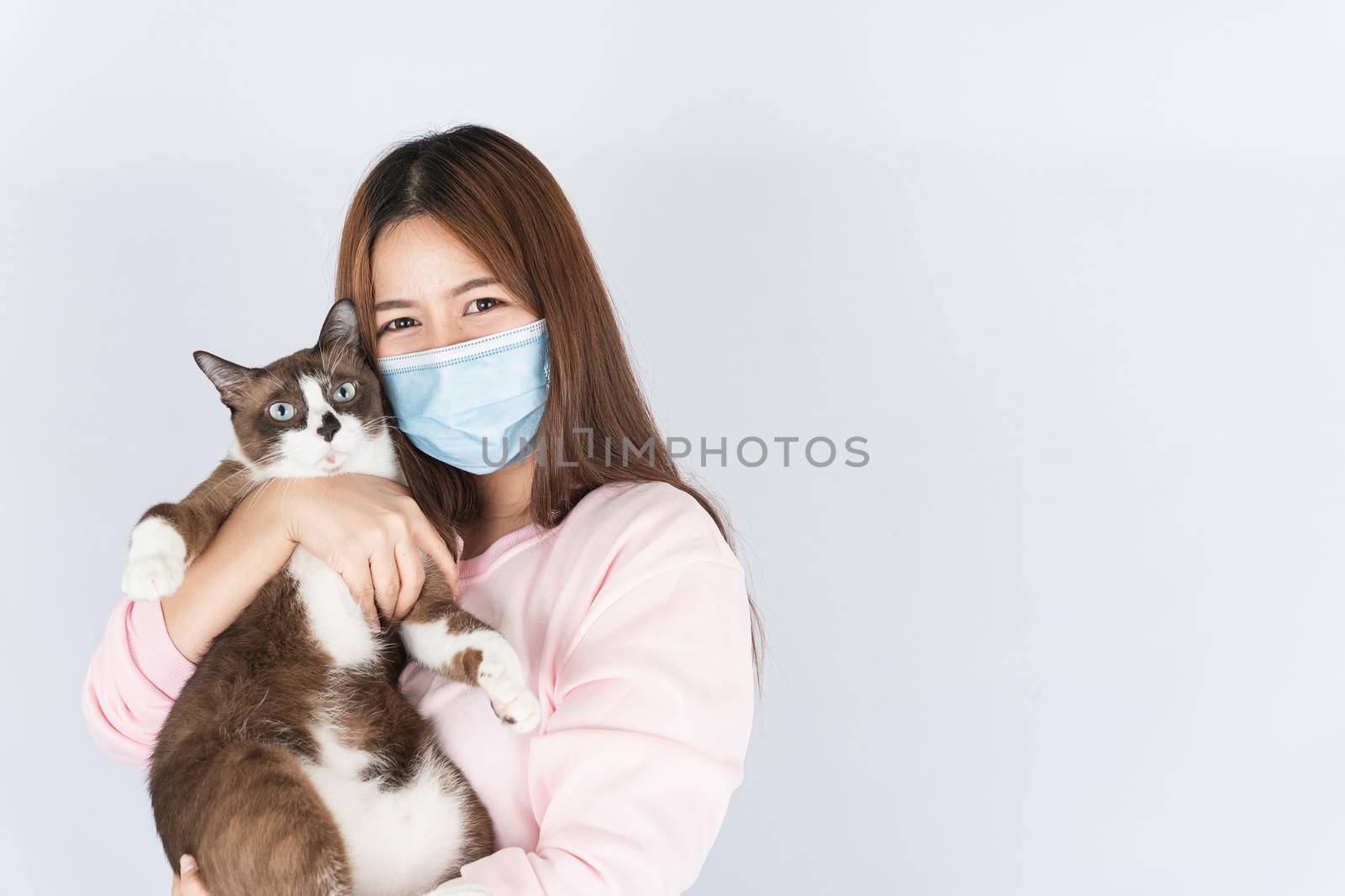 Asian beautiful happy woman wearing a medical protection face mask for protect the coronavirus, filter dust PM 2.5, cold and allergic to cat fur and she carry a cat on the white background