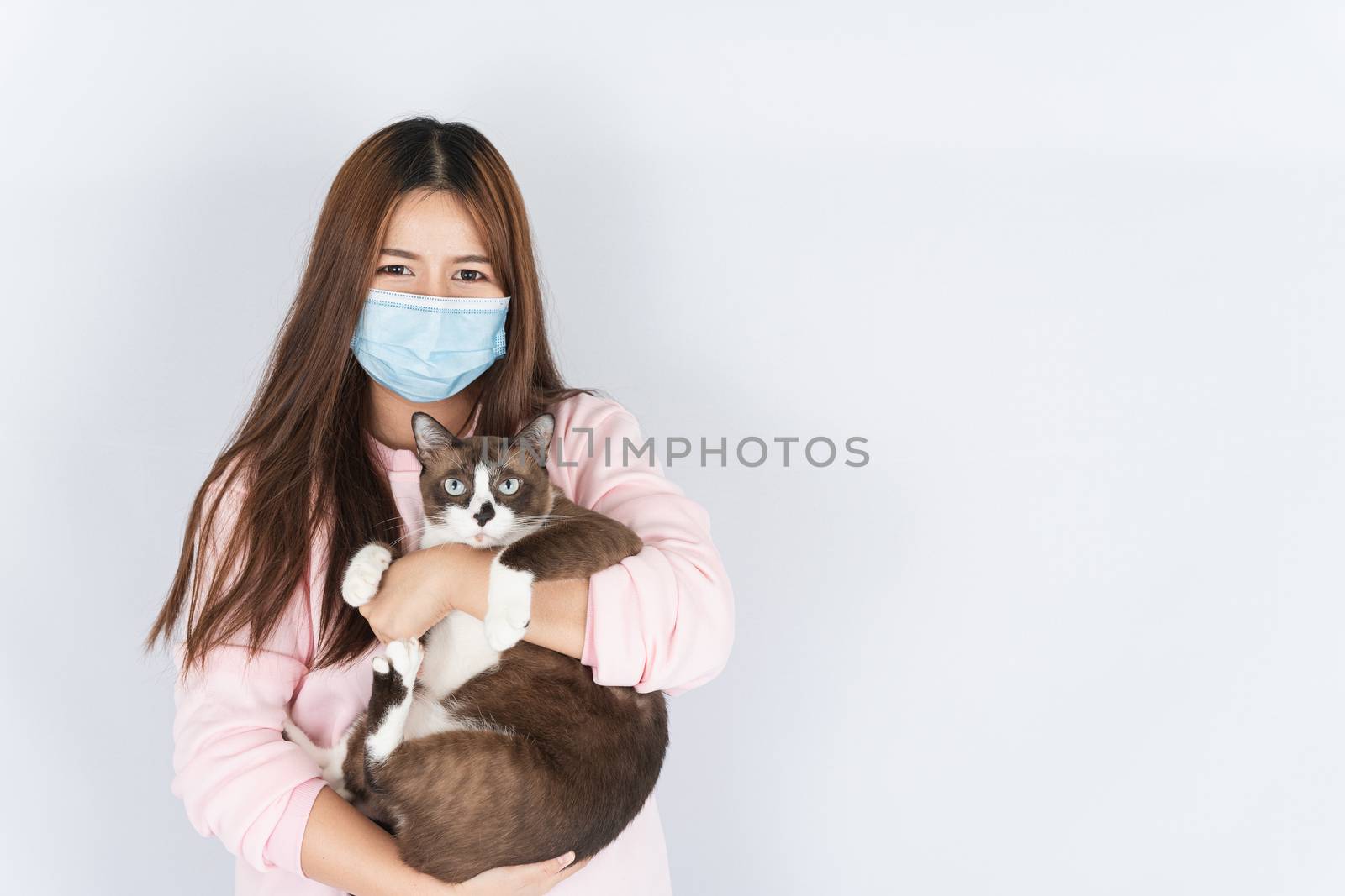 Asian beautiful happy woman wearing a medical protection face mask for protect the coronavirus, filter dust PM 2.5, cold and allergic to cat fur and she carry a cat on the white background