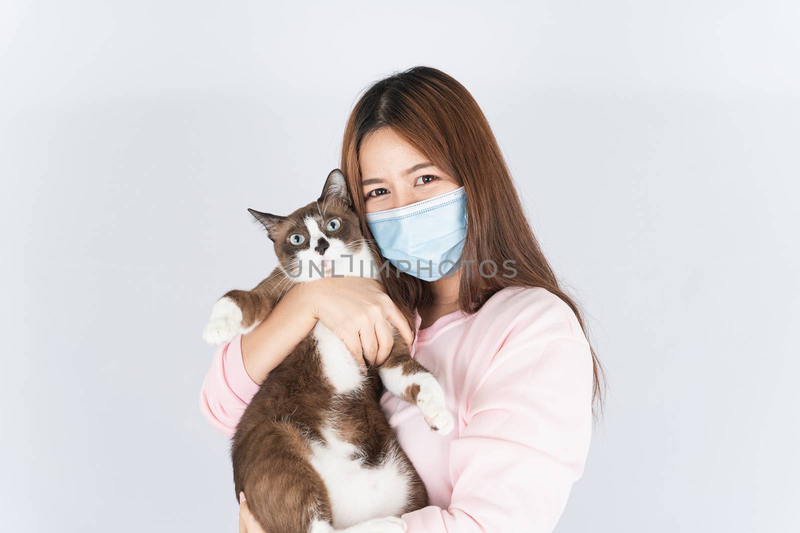 Asian beautiful happy woman wearing a medical protection face mask for protect the coronavirus, filter dust PM 2.5, cold and allergic to cat fur and she carry a cat on the white background