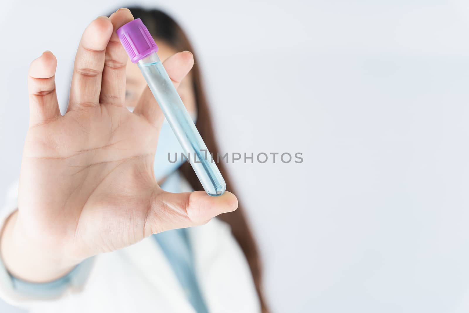 Closeup hand of woman doctor or scientist wearing medical mask and holding medicine liquid vaccine vial bottle. COVID 19 or coronavirus concept.