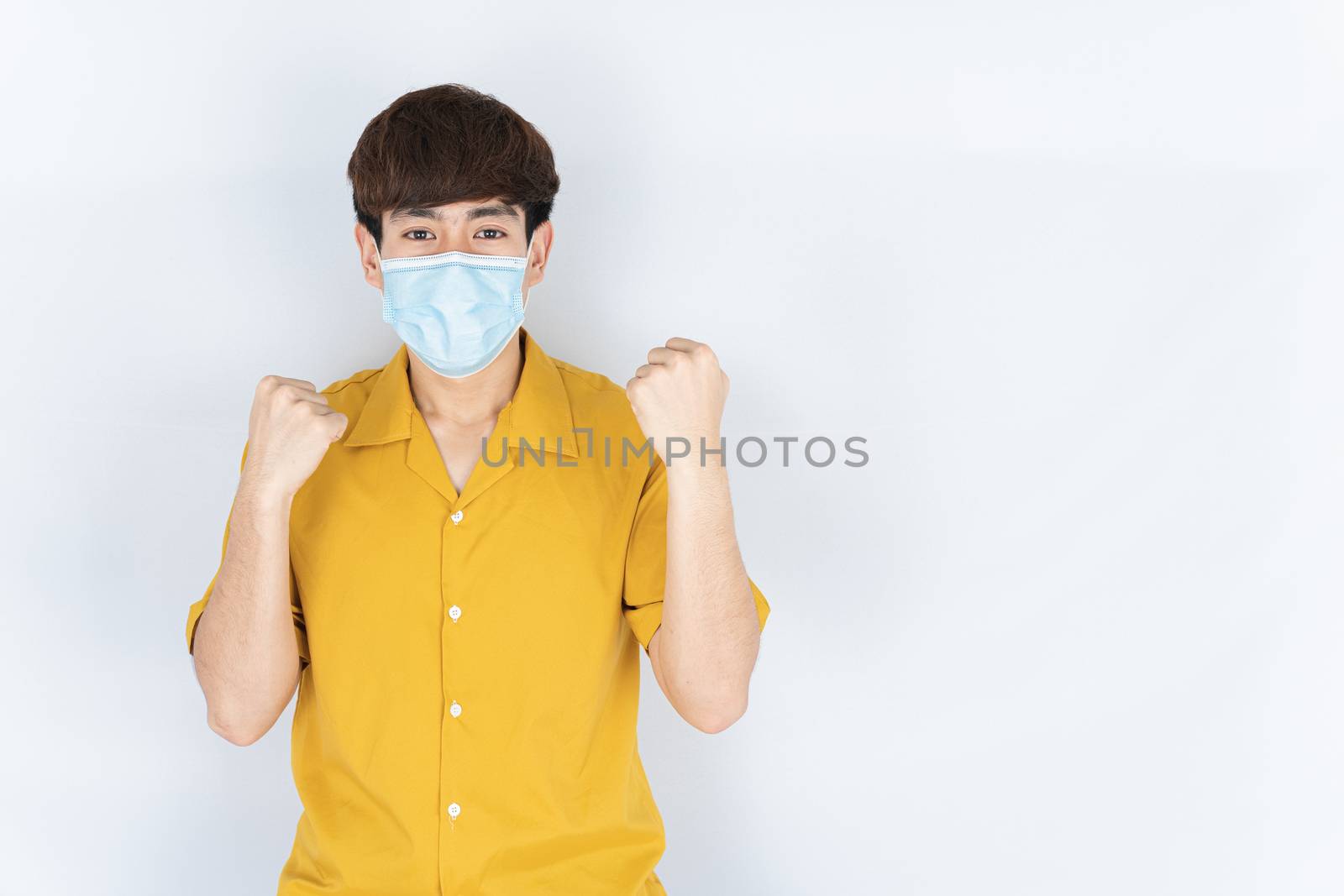 Asian handsome happy hipster man wearing a medical protection face mask for protect the coronavirus, filter dust PM 2.5 and cold and raise her hand to fight them on white background