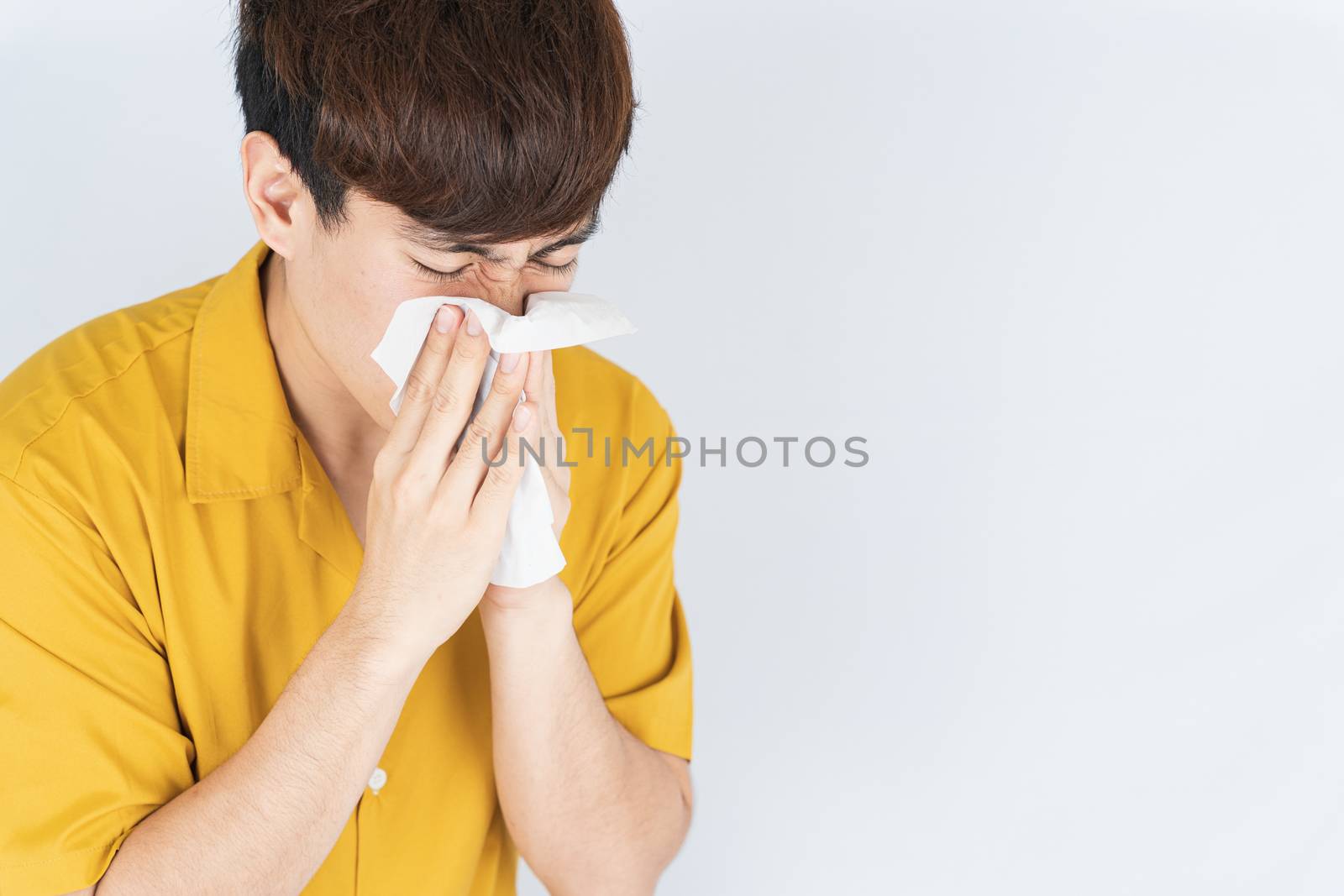 Asian handsome happy hipster man blowing a nose to tissue paper from the coronavirus, dust PM 2.5 and cold on white background