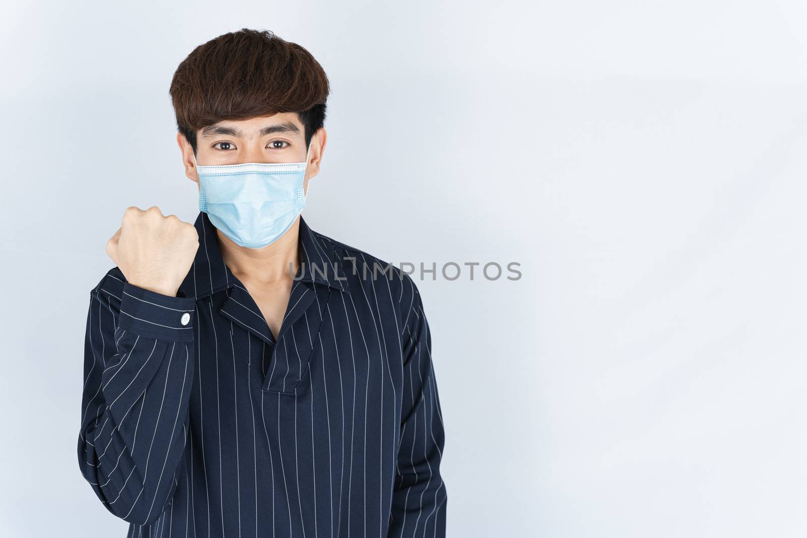 Asian handsome happy hipster man wearing a medical protection face mask for protect the coronavirus, filter dust PM 2.5 and cold and raise her hand to fight them on white background