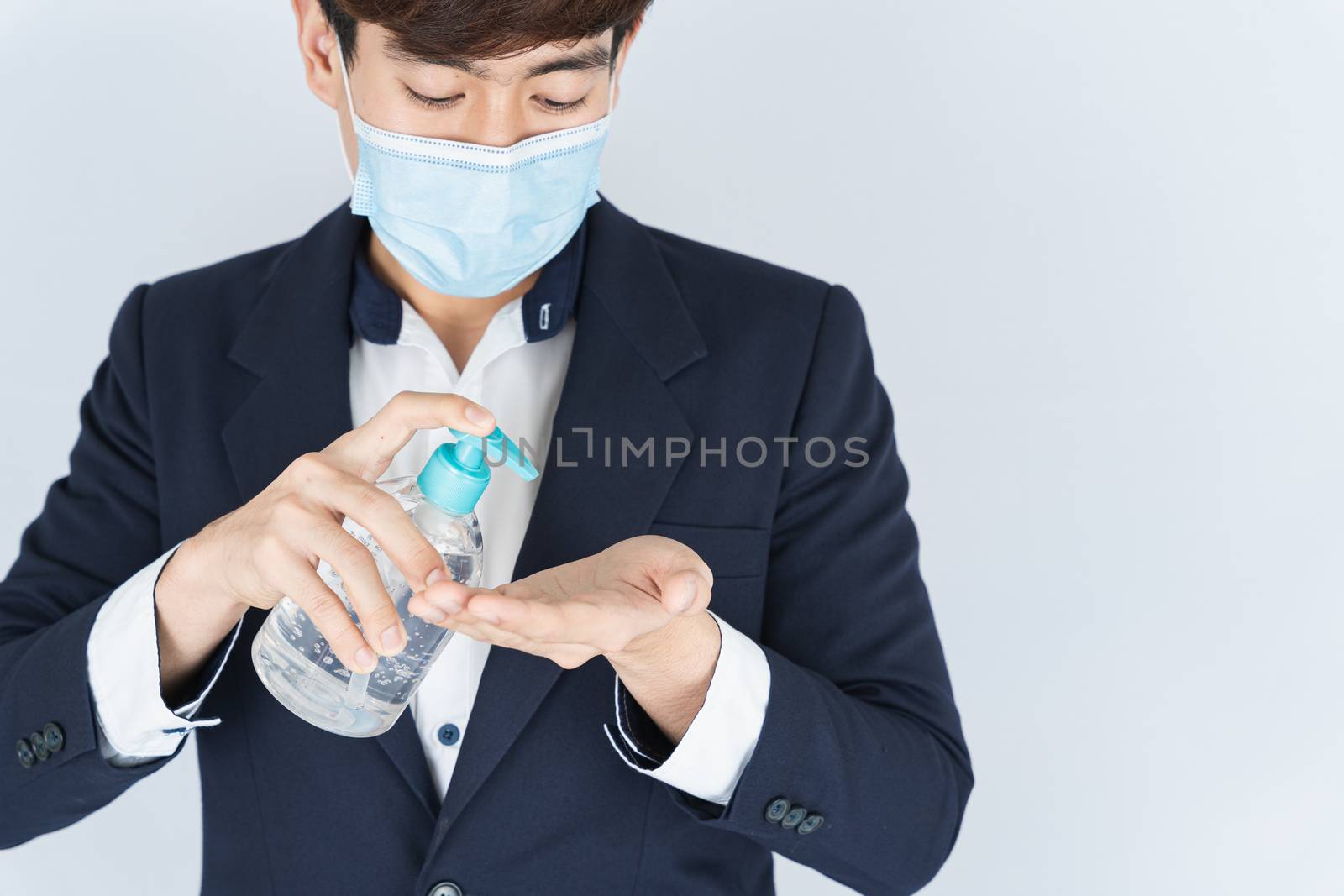 Asian handsome happy business man wearing a medical protection face mask for protect the coronavirus, filter dust PM 2.5 and cold and using sanitizer hand gel on white background