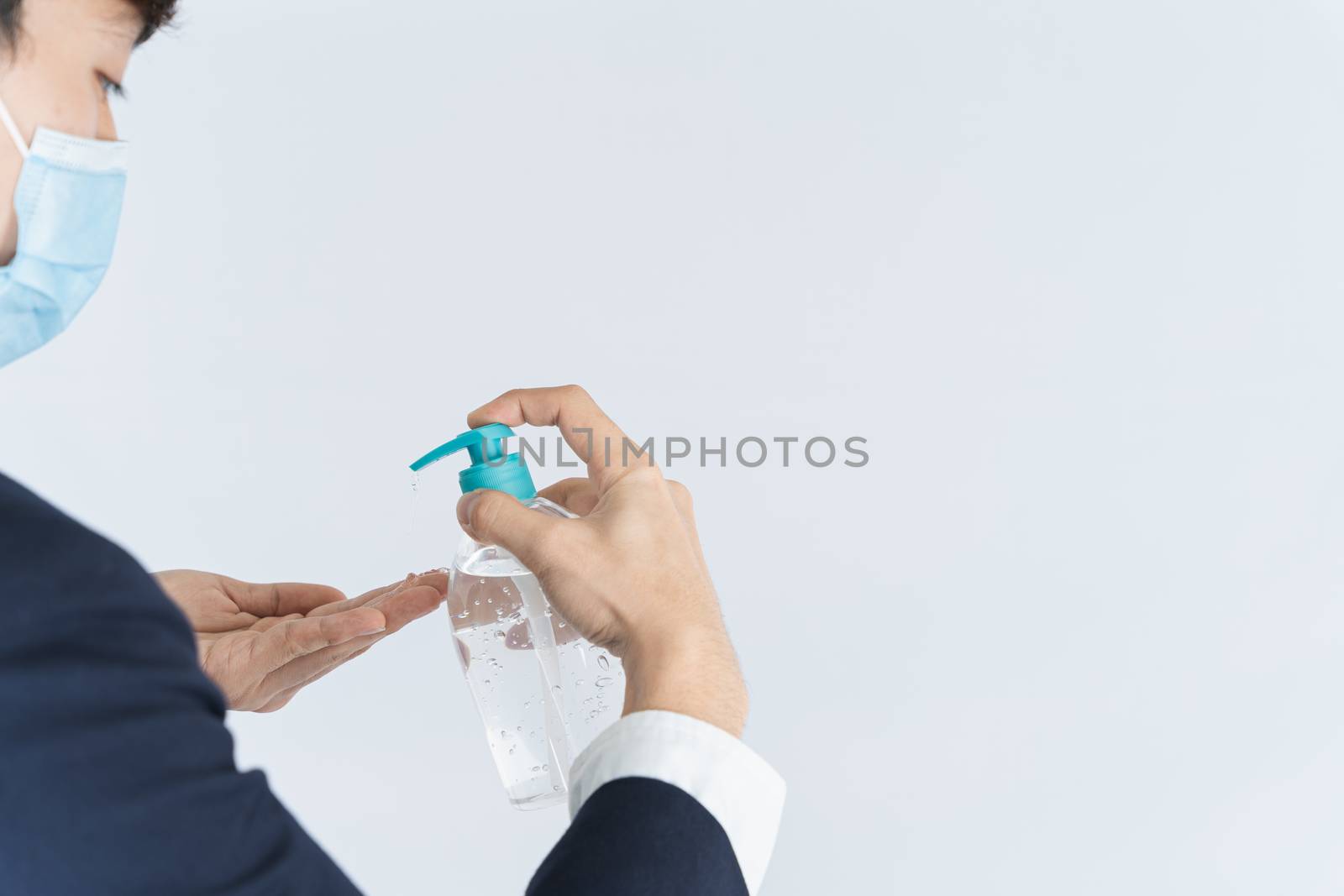 Asian handsome happy business man wearing a medical protection face mask for protect the coronavirus, filter dust PM 2.5 and cold and using sanitizer hand gel on white background