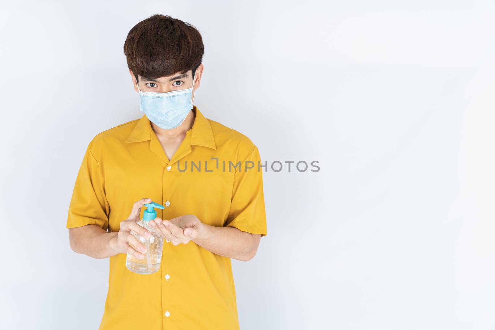 Asian handsome happy hipster man wearing a medical protection face mask for protect the coronavirus, filter dust PM 2.5 and cold and using sanitizer hand gel on white background