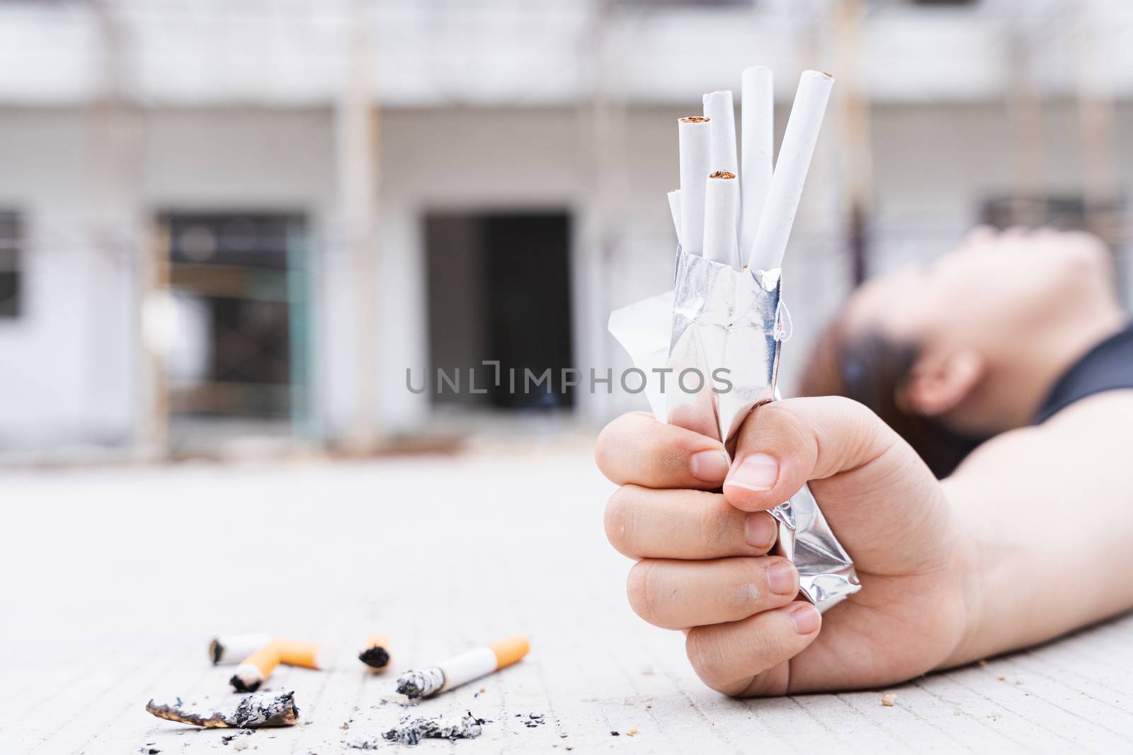 Close-up young woman 's hand crushes pack of cigarette and lying on the floor. World no tobacco day.