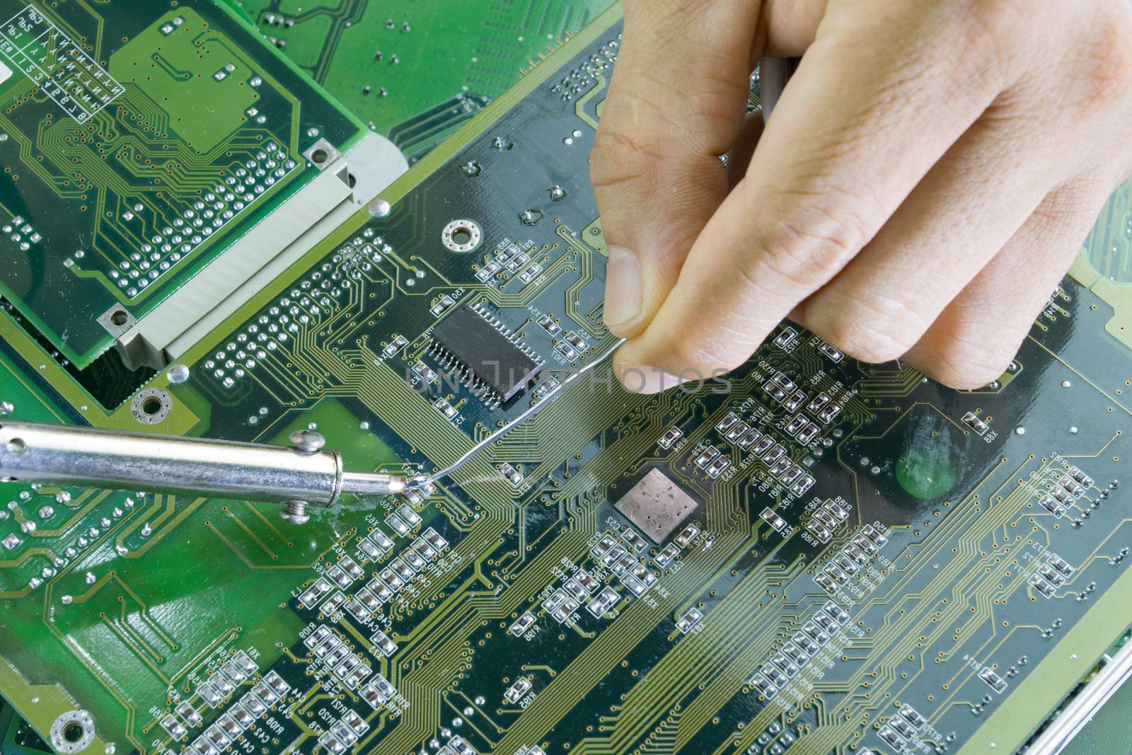 Technicians are using a soldering iron for repairing electronic of the computer circuit board concept technology of computer circuit hardware.