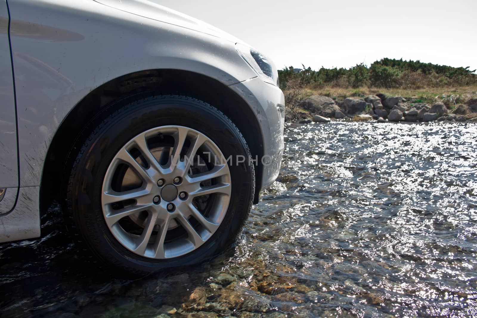 Off-road vehicle drives over water of a river. by Arkadij