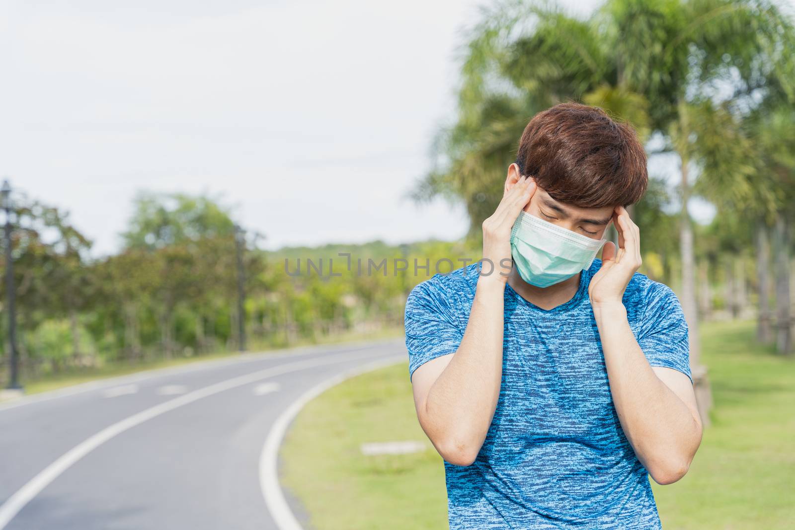 Young male wearing medical mask have headache while workout at t by mikesaran