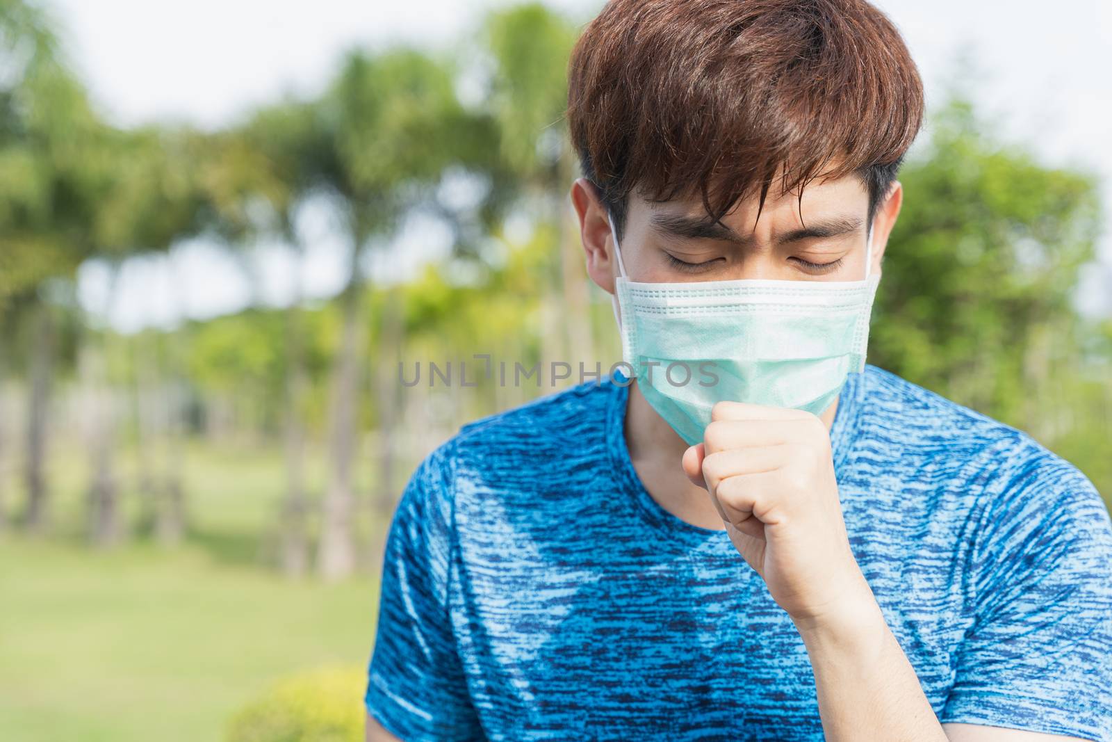 Young male wearing medical mask and coughing while workout at th by mikesaran
