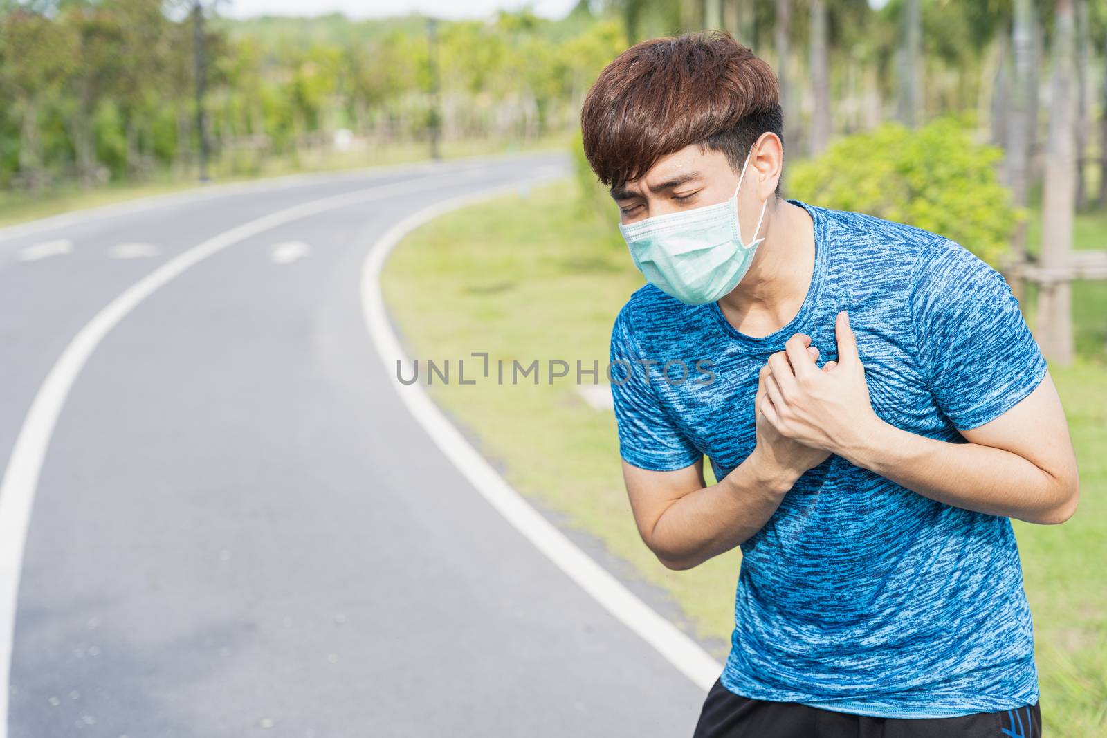 Young male wearing medical mask have headache while workout at the park. Stay in fit during quarantine in the days of the Corona Virus or Covid-19