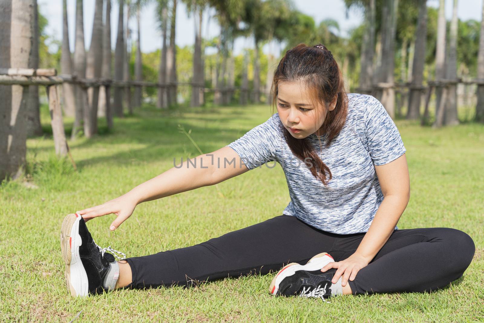 Young female stretching her legs before workout training session at the park. Healthy young woman warming up outdoors. Healthy and Lifestyle Concept.
