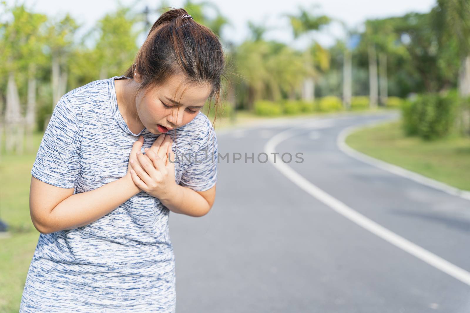 Exhausted female runner suffering painful angina pectoris or asthma breathing problems after training hard on summer. Running over training consequence.