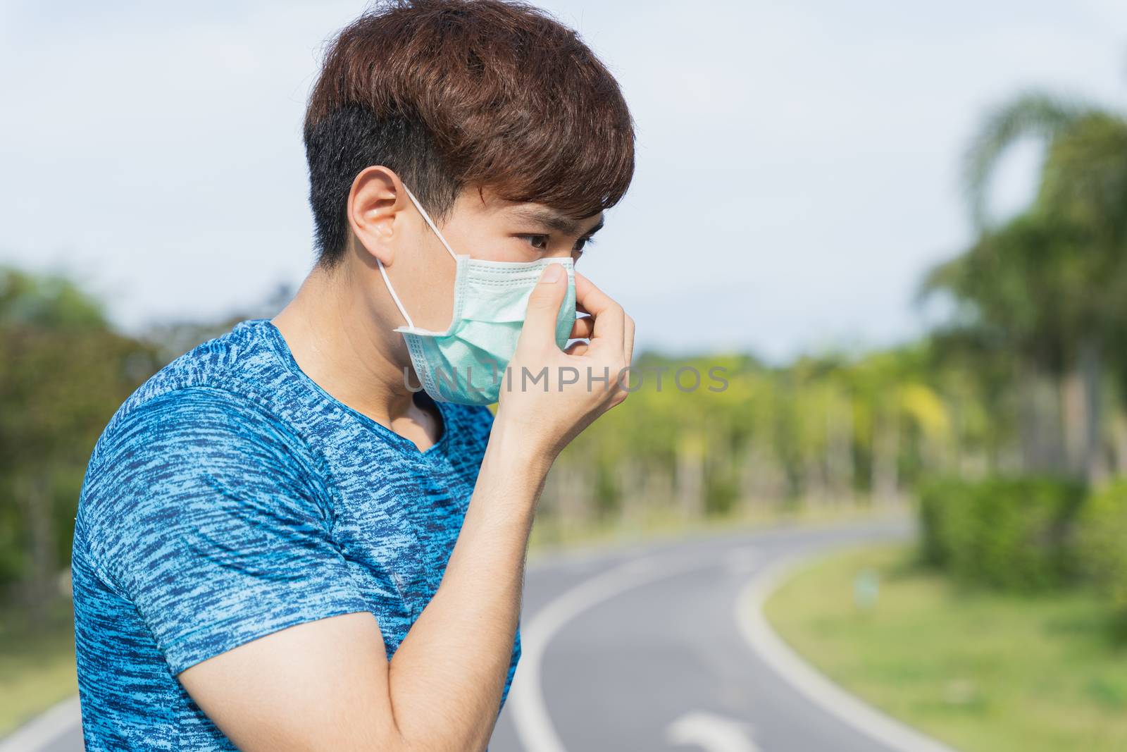 Young male wearing medical mask before workout training session at the park. Stay in fit during quarantine in the days of the Corona Virus or Covid-19