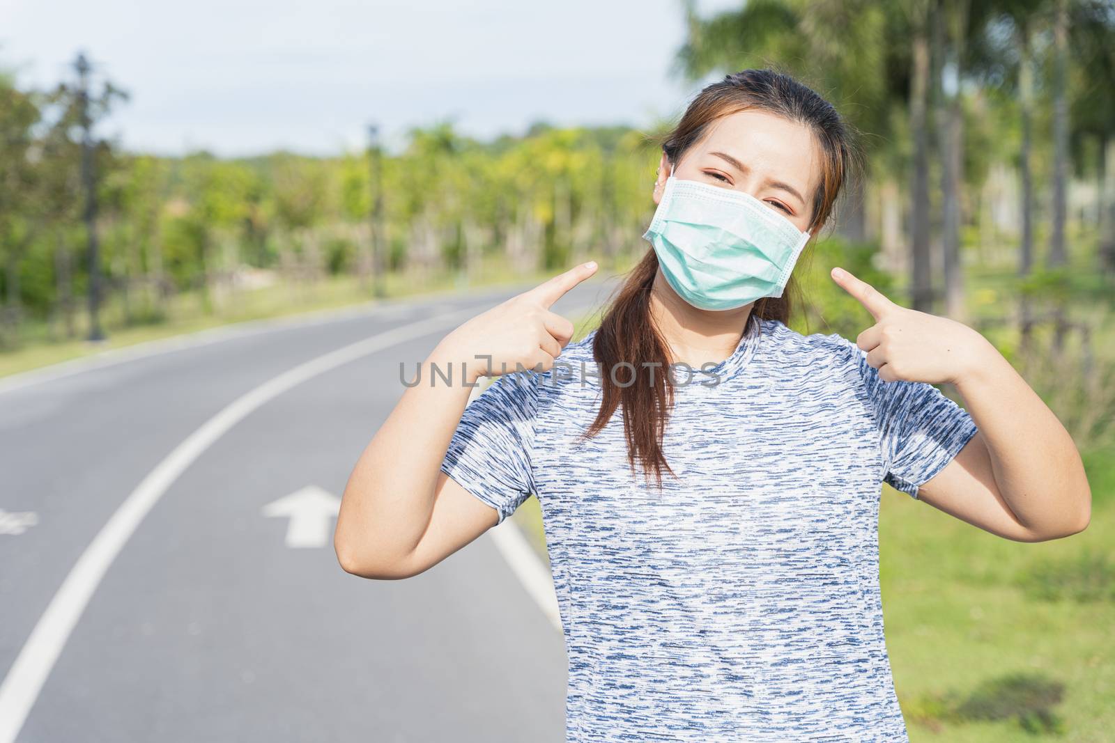 Young female pointing at the medical mask before workout trainin by mikesaran