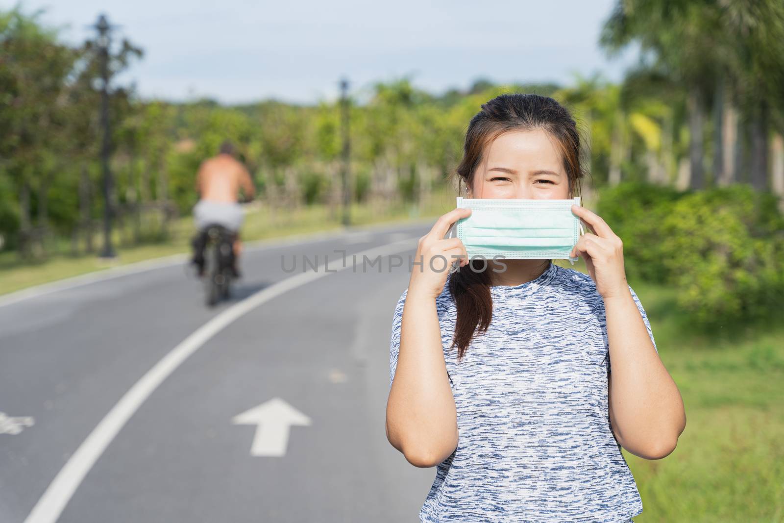 Young female wearing medical mask before workout training session at the park. Stay in fit during quarantine in the days of the Corona Virus or Covid-19