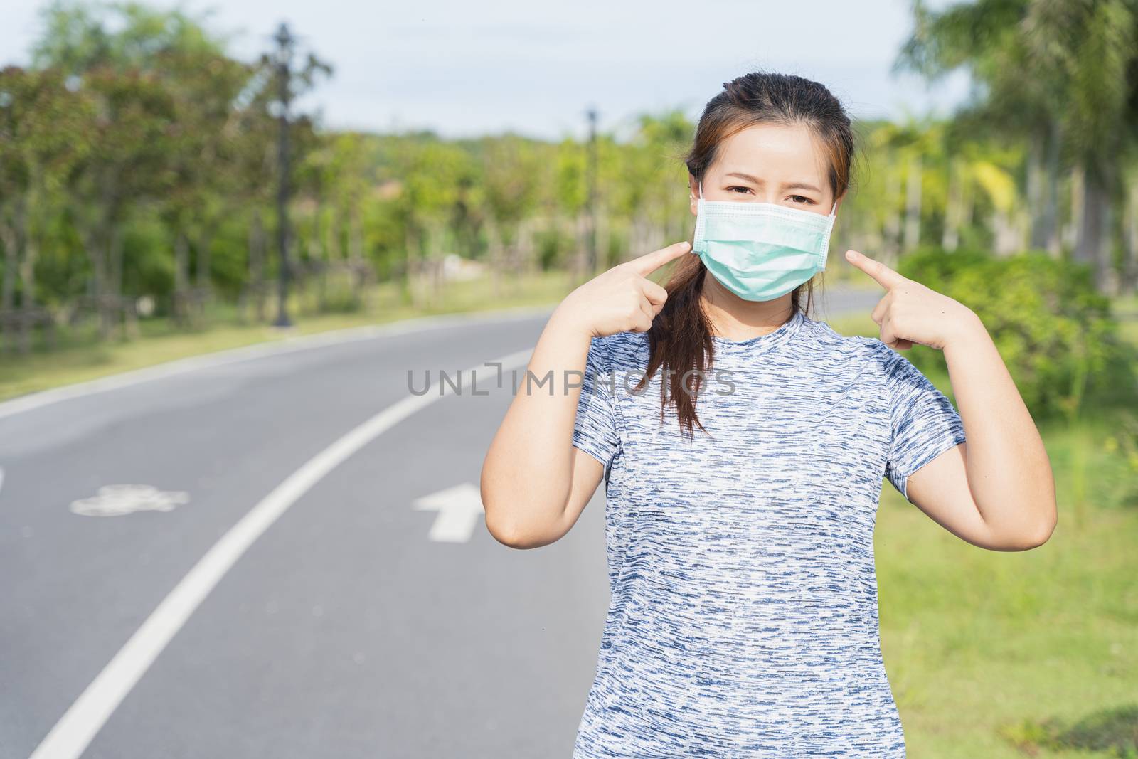 Young female pointing at the medical mask before workout trainin by mikesaran