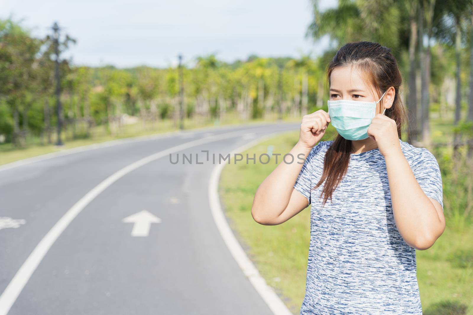Young female wearing medical mask before workout training session at the park. Stay in fit during quarantine in the days of the Corona Virus or Covid-19