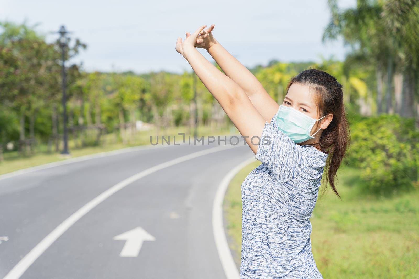 Young female wearing medical mask and stretching his arms before by mikesaran