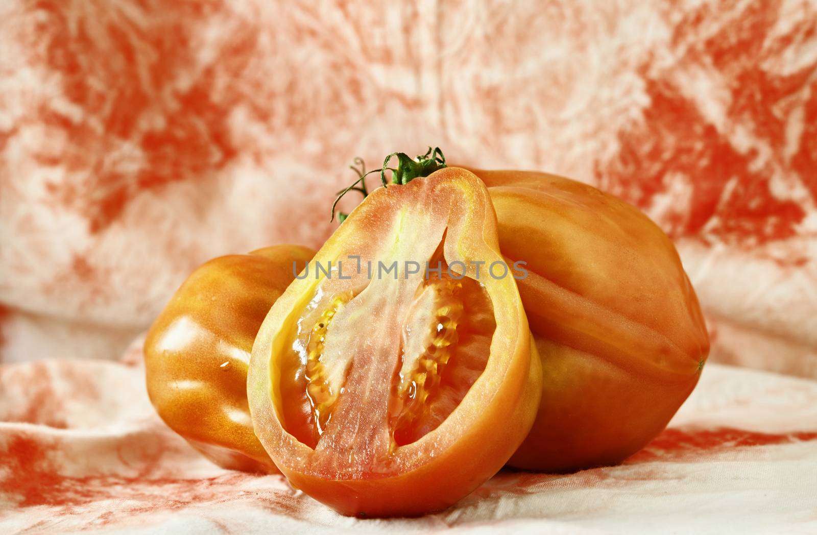 Red beefsteak tomatoes -beef tomato or coeur de boeuf -, large and flavor variety of tomato , ,in the foreground a tomato cut in half with bright seeds ,white- red background 