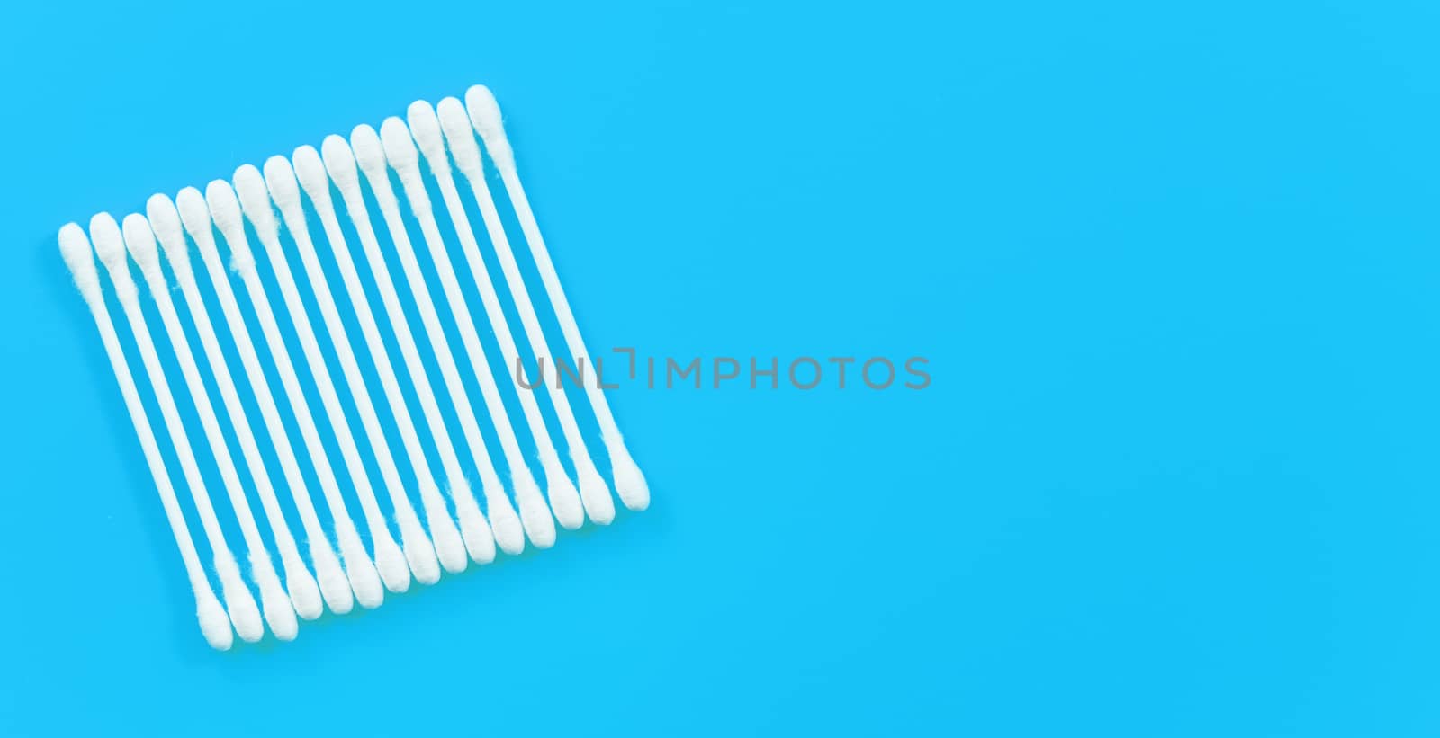 Cotton buds or swabs arranged in square on light blue desk, view from above, space for text right side.