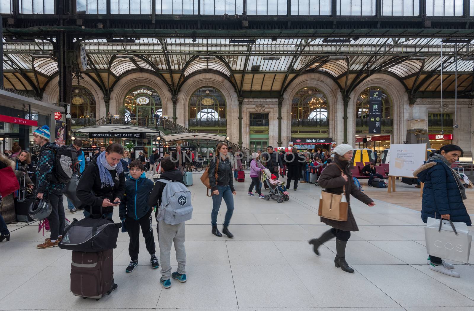 Paris, France -- November 4, 2017 -- Mother with 2 young boys checks her mobile phone in the bustling Gare de Lyon train station in Paris.