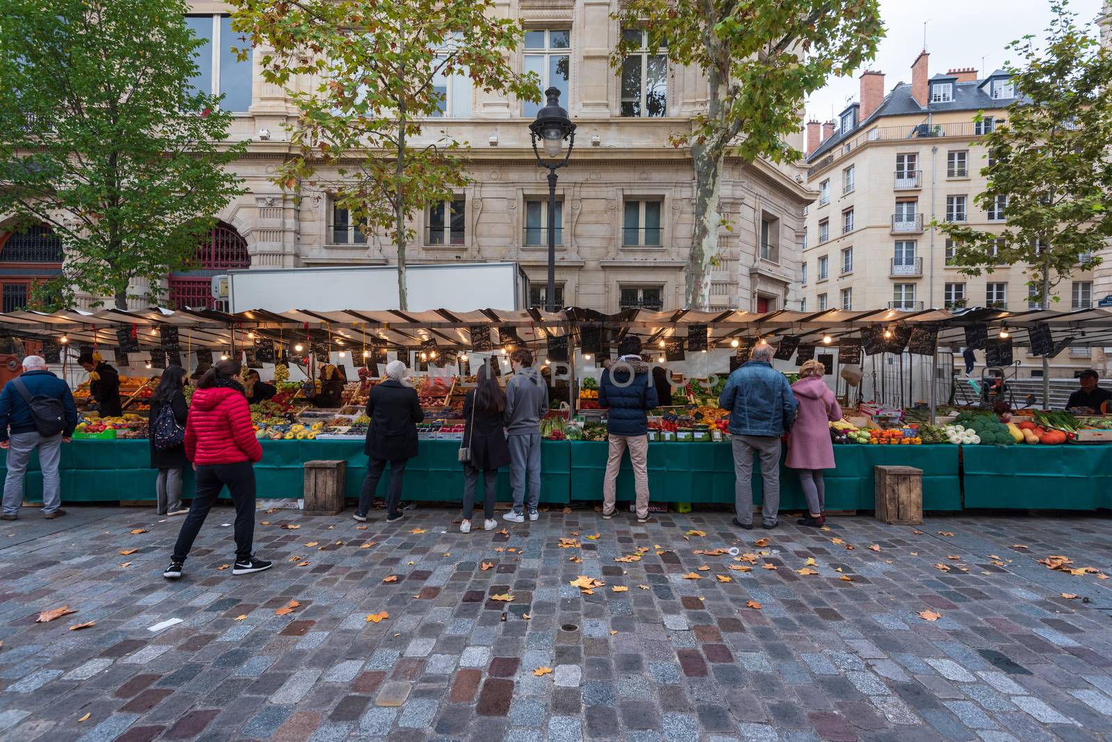 Marais, Paris, France --November 4, 2017. An ultra wide angle photo of Parisians shopping for groceries in a Farmers Market in the Marais section of Paris.