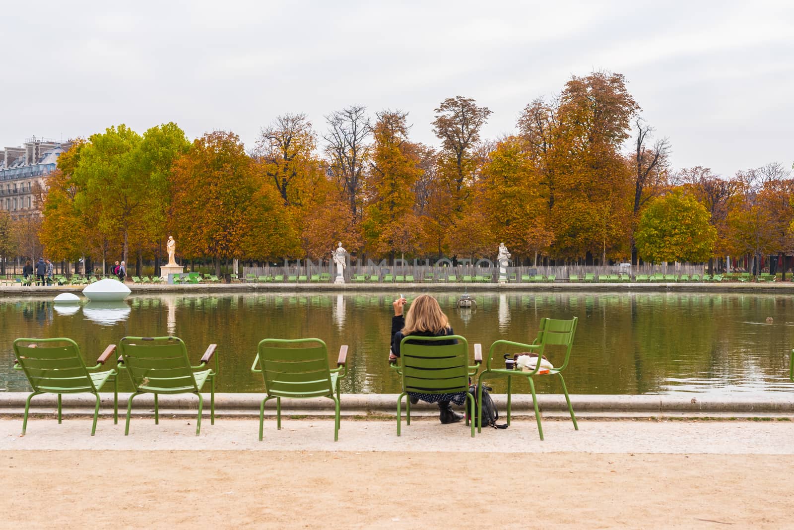 Paris, France -- November 3, 2017 -- Woman having a smoke by the pond in the Tuileries Gardens.