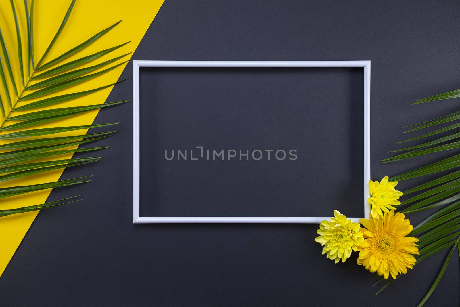 Frame of tropical palm leaves and flowers on black and yellow background. Flat lay, top view, copy space. Summer background, nature. Creative frame background with tropical leaves.