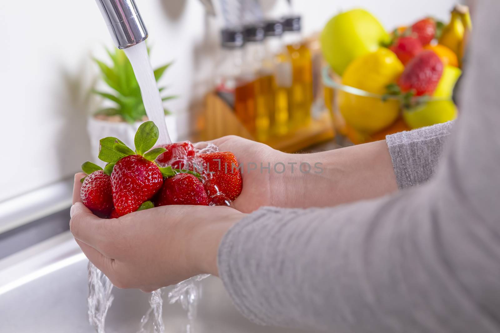 Woman hands washing strawberries in the kitchen. Eating fresh and healthy fruits concept. Closeup