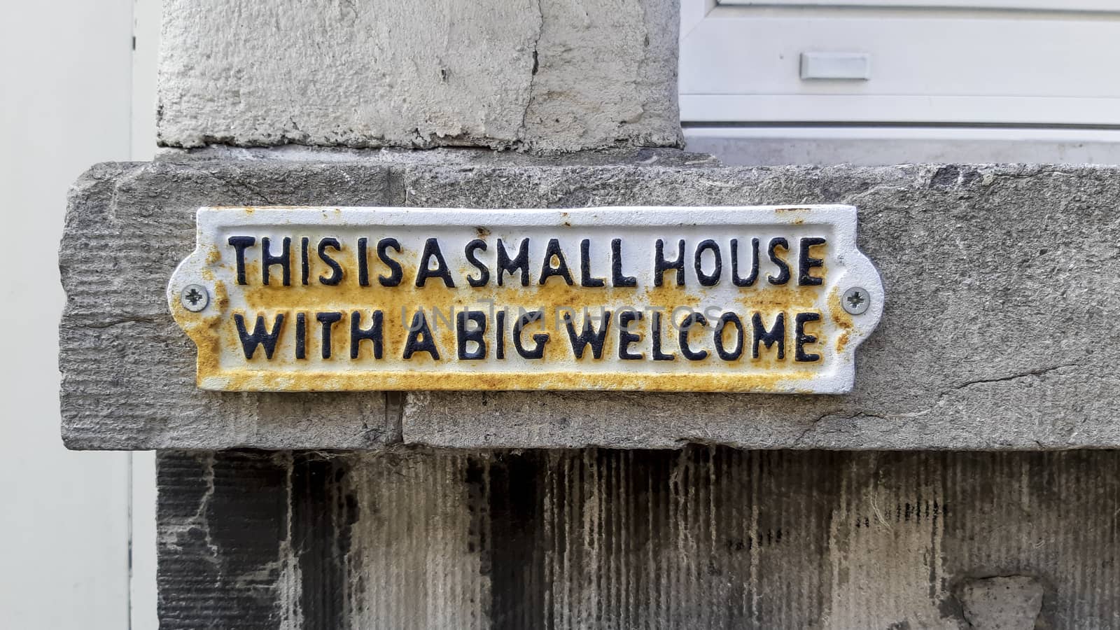 This is a small house with a big welcome sign on a residential house in the city by kb79