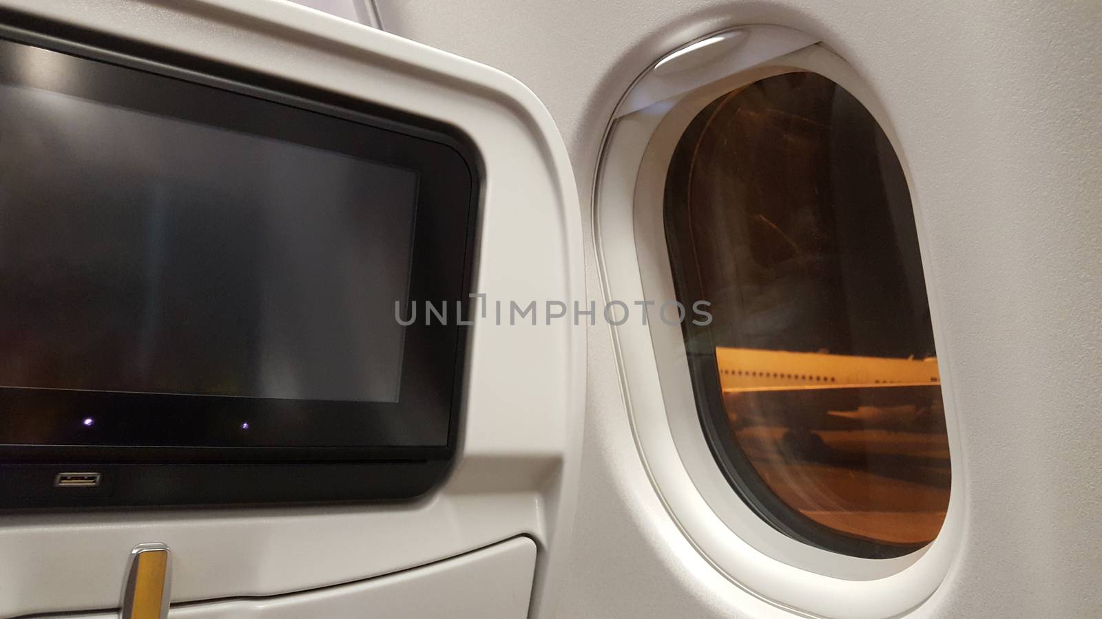 View from the airplane window of an airport in the dark. White and orange.