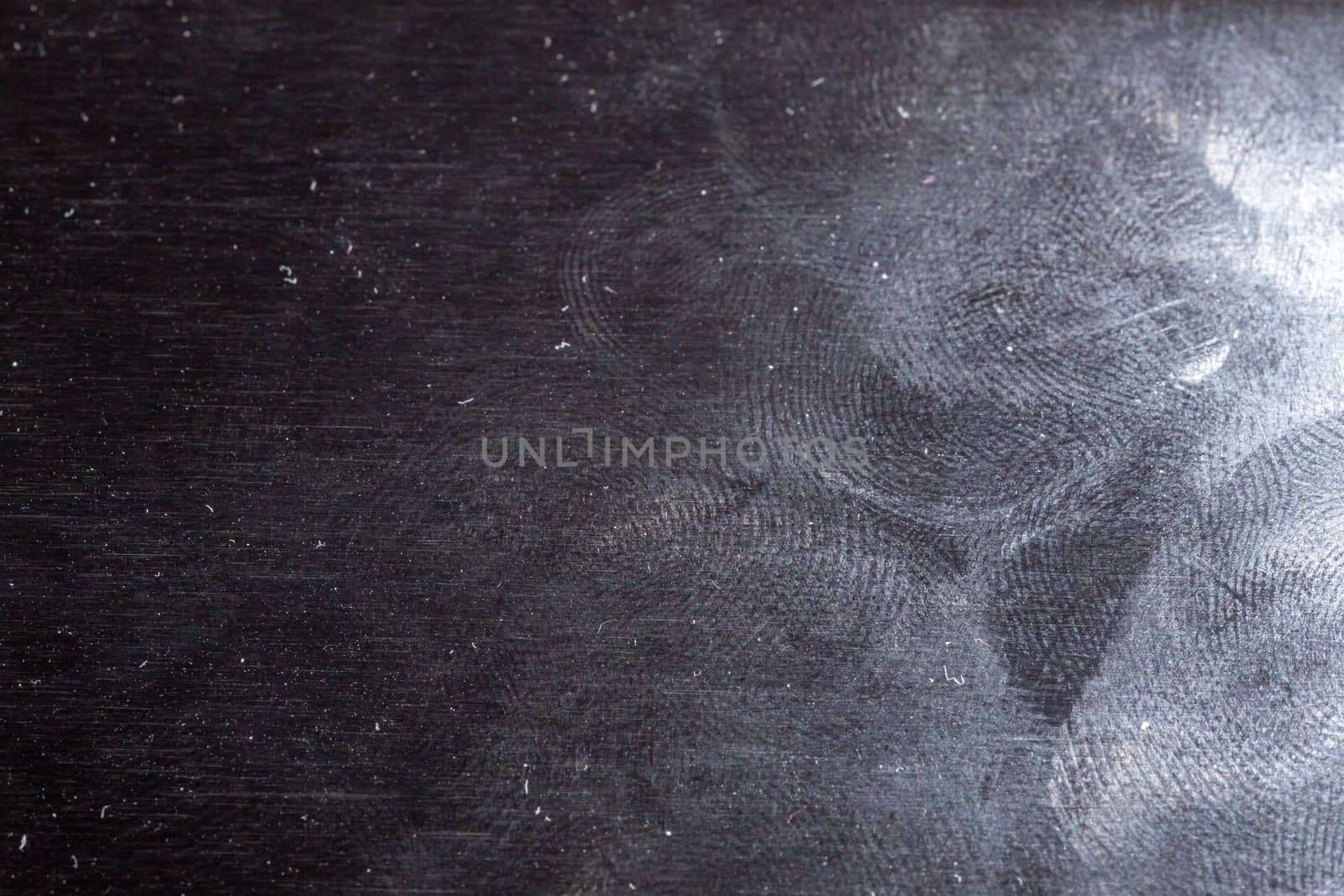 oily gloss black steel surface with many fingerprints - closeup with selective focus.