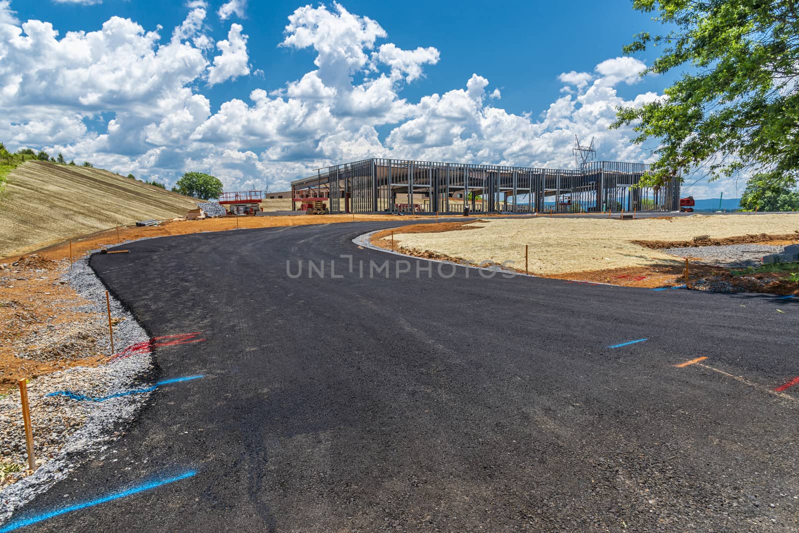 Horizontal shot of a fresh blacktopped road leading up to a commercial construction site.