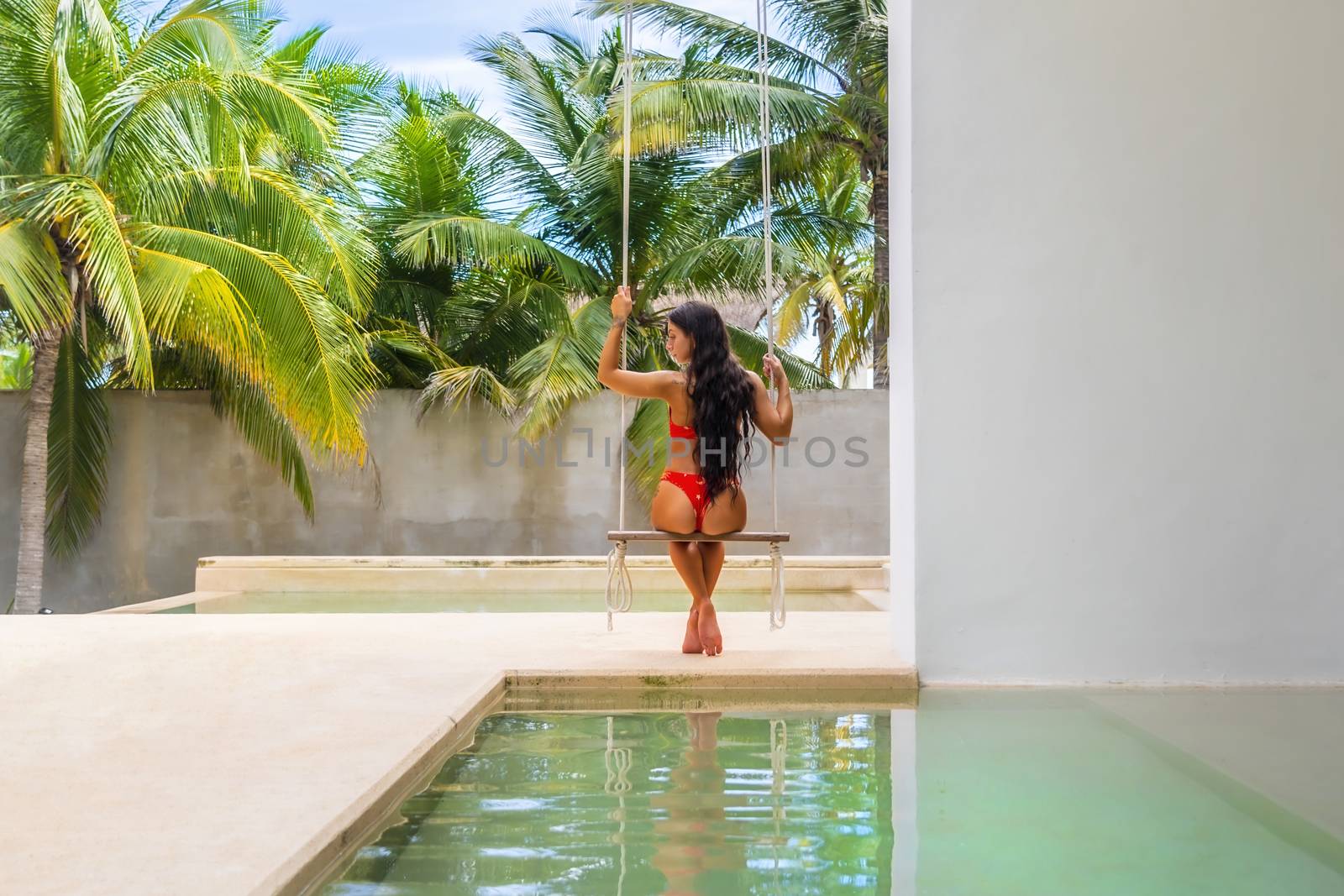 A beautiful brunette bikini model swings by the pool in the Yucatán Peninsula near Merida, Mexico